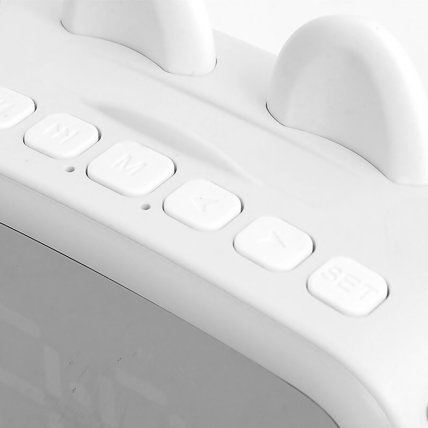 Primer plano de botones blancos en un dispositivo blanco, incluyendo 'M' y 'SET'.