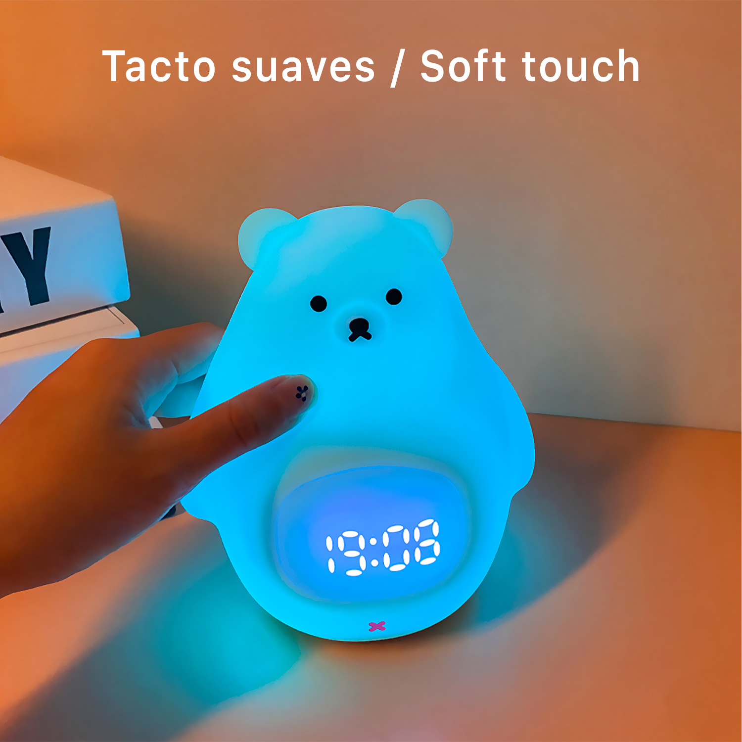 Luz nocturna azul con forma de oso con un reloj digital que muestra 19:08, apoyada en una mesa.