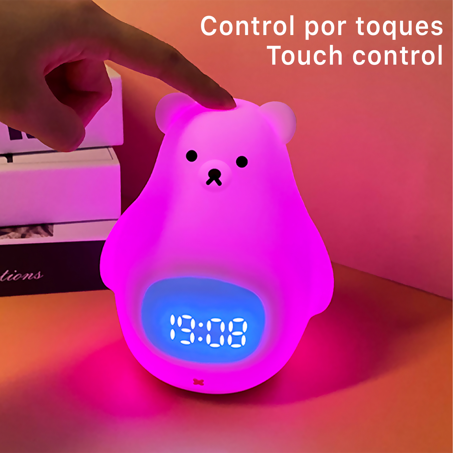 Una luz nocturna rosa en forma de oso con pantalla digital. Un dedo toca la luz.
