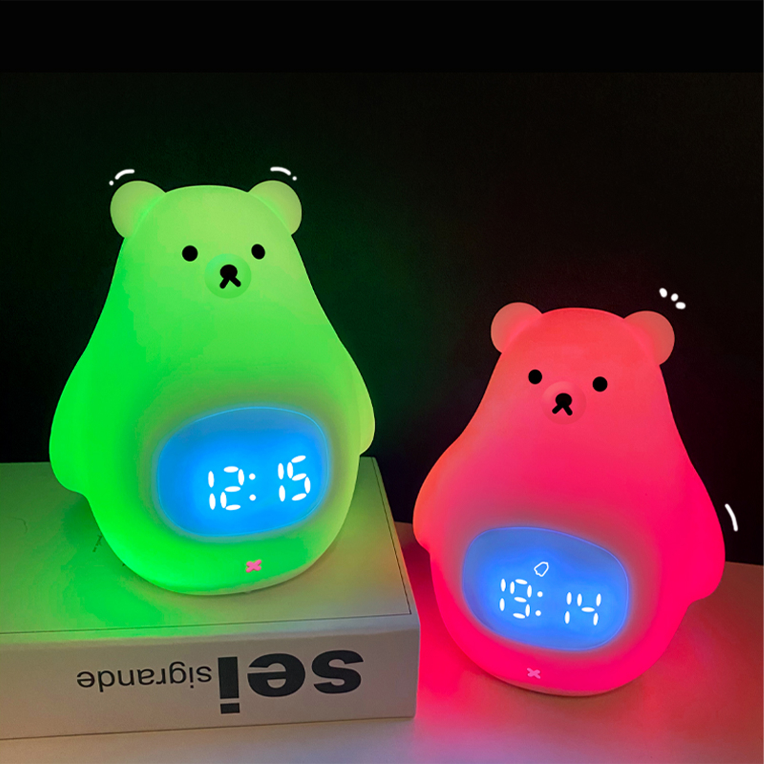 Dos luces de noche con forma de oso, una verde, otra rosa. Ambas muestran la hora en su vientre.