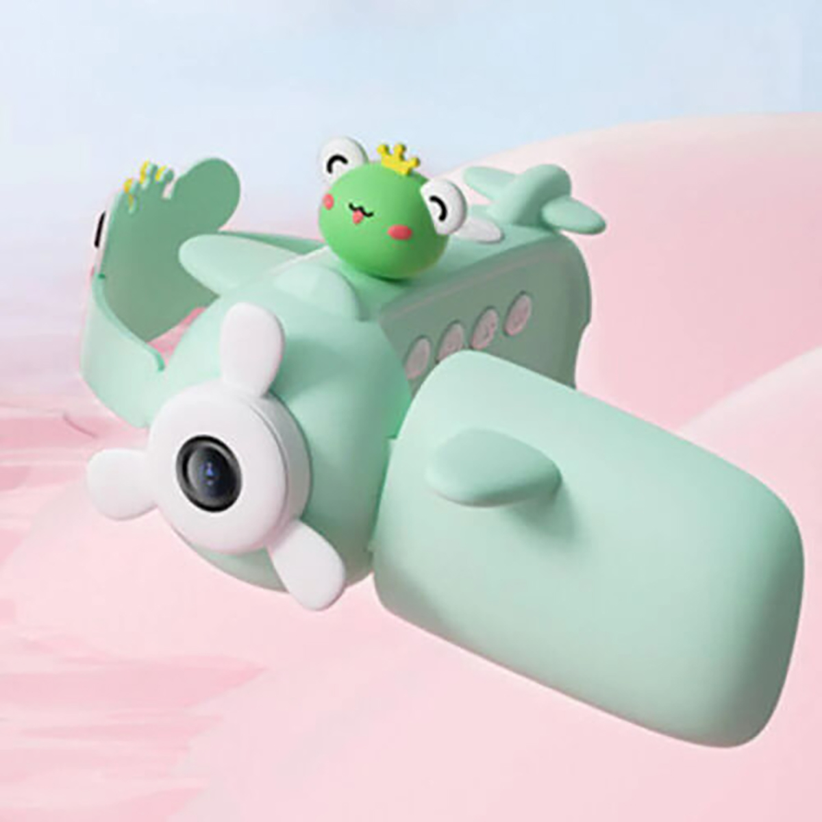 Un avión de juguete verde menta con una rana encima. Está sobre un fondo rosa. El avión tiene una hélice y una cámara.
