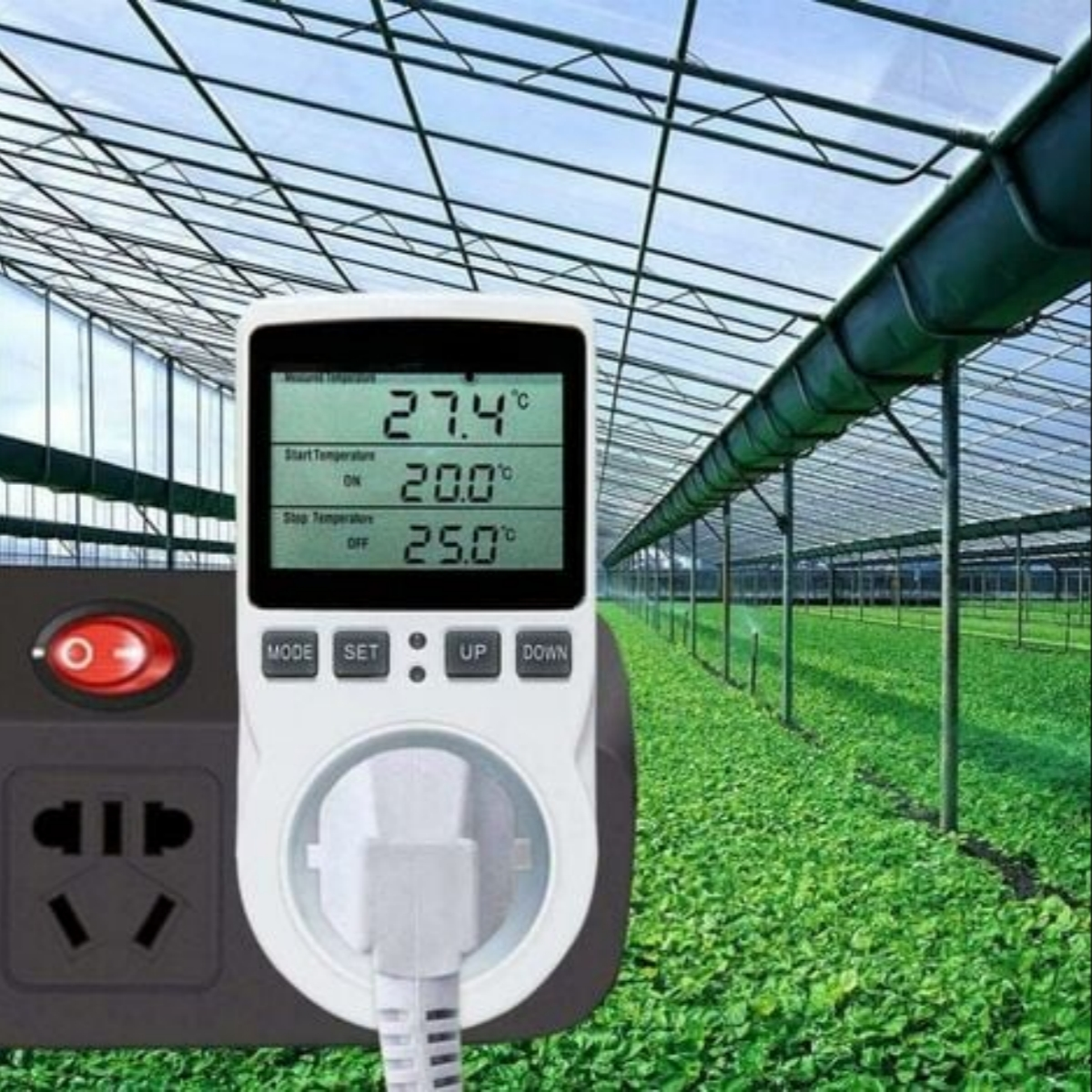 Ein digitaler Temperaturregler zeigt 27,4°C in einem Gewächshaus an, mit einem Netzstecker in der Nähe.