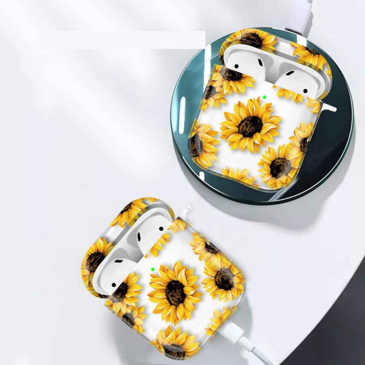 Weiße kabellose Ohrhörer in einer Sonnenblumen-gemusterten Hülle auf einem kabellosen Ladegerät. Eine zweite Hülle ist sichtbar.