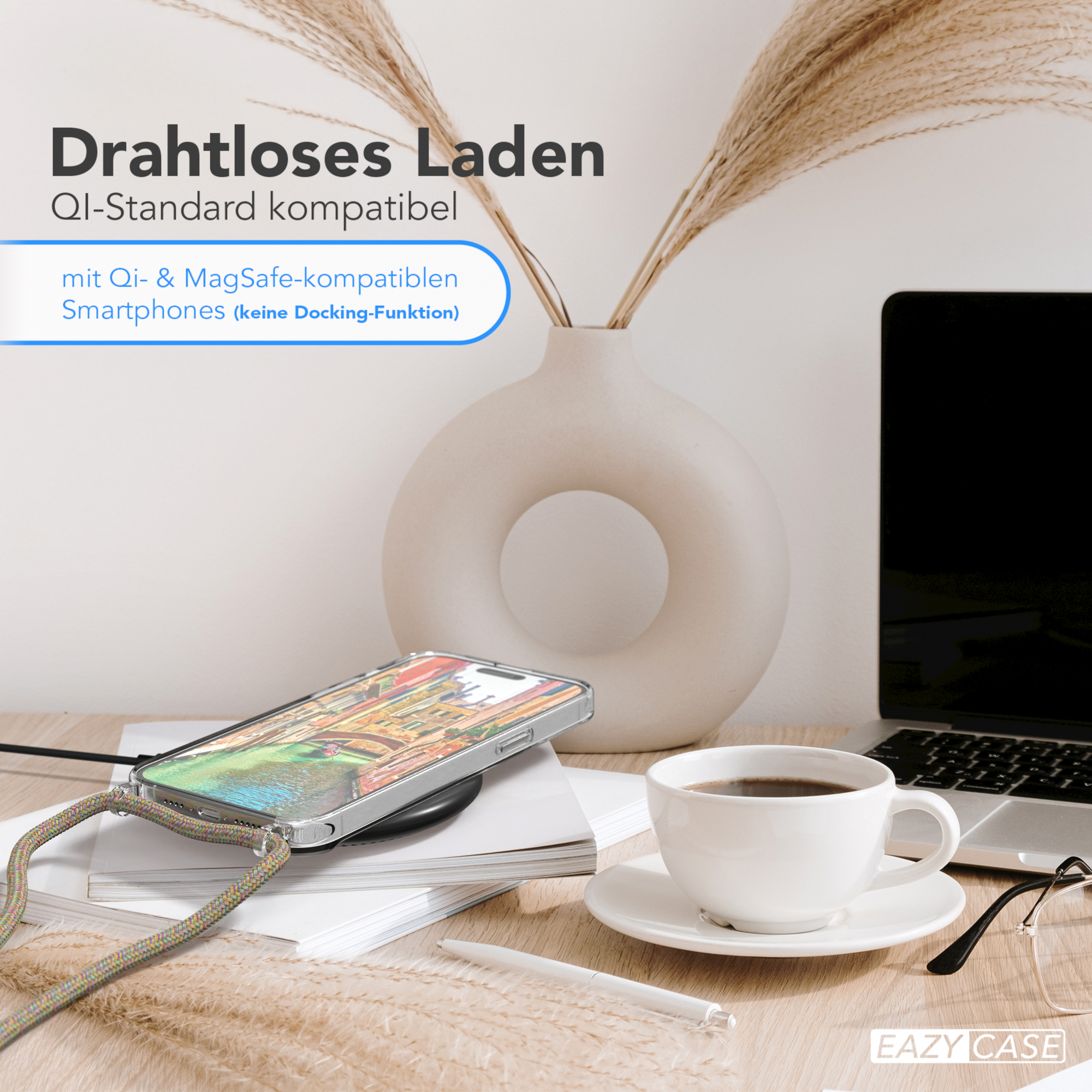 Telefon auf kabellosem Ladegerät, Kaffee, Blumen in Vase, Laptop und Stift auf Holztisch.