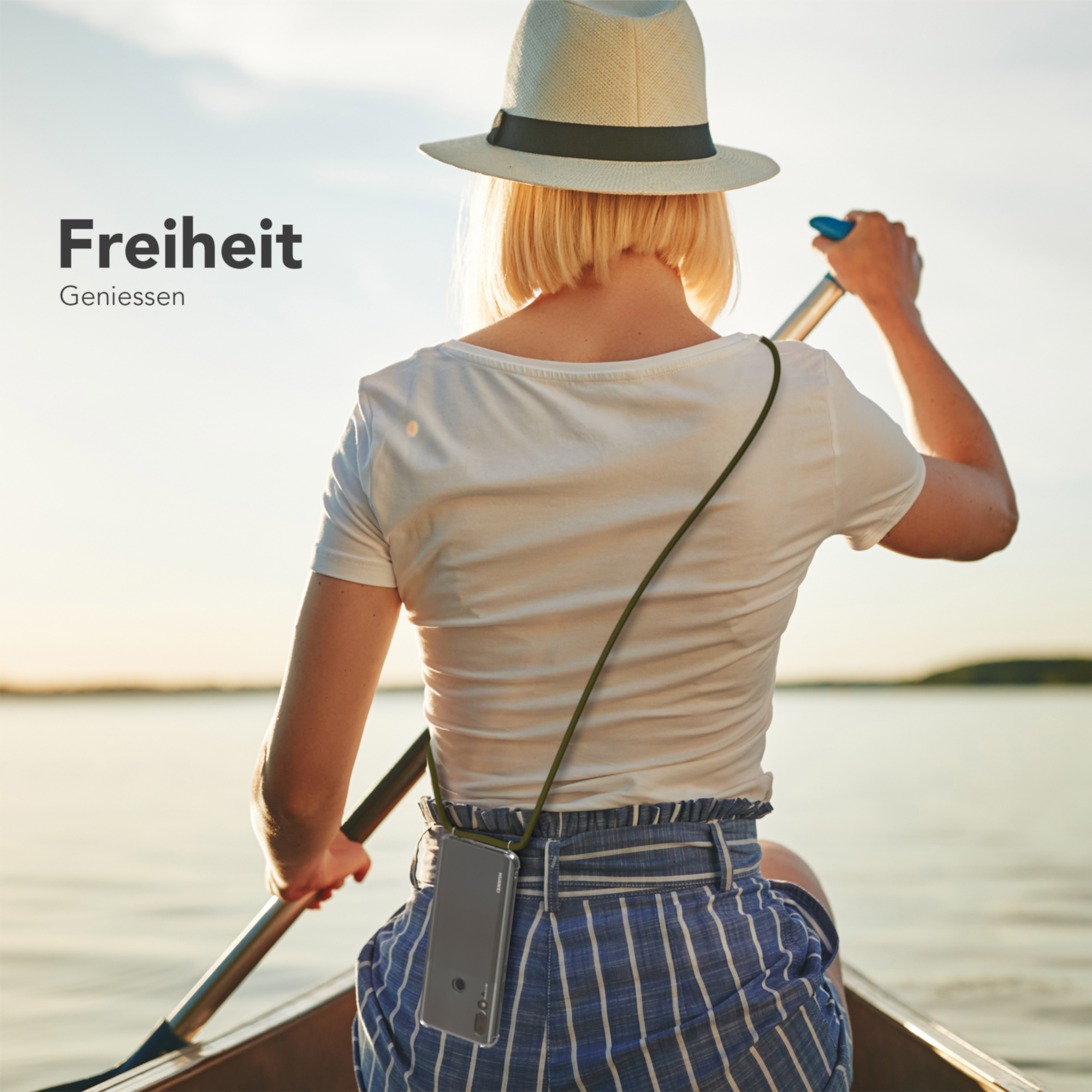 Eine Frau rudert in einem Boot auf einem See und hält ein Telefon an einer Schnur.