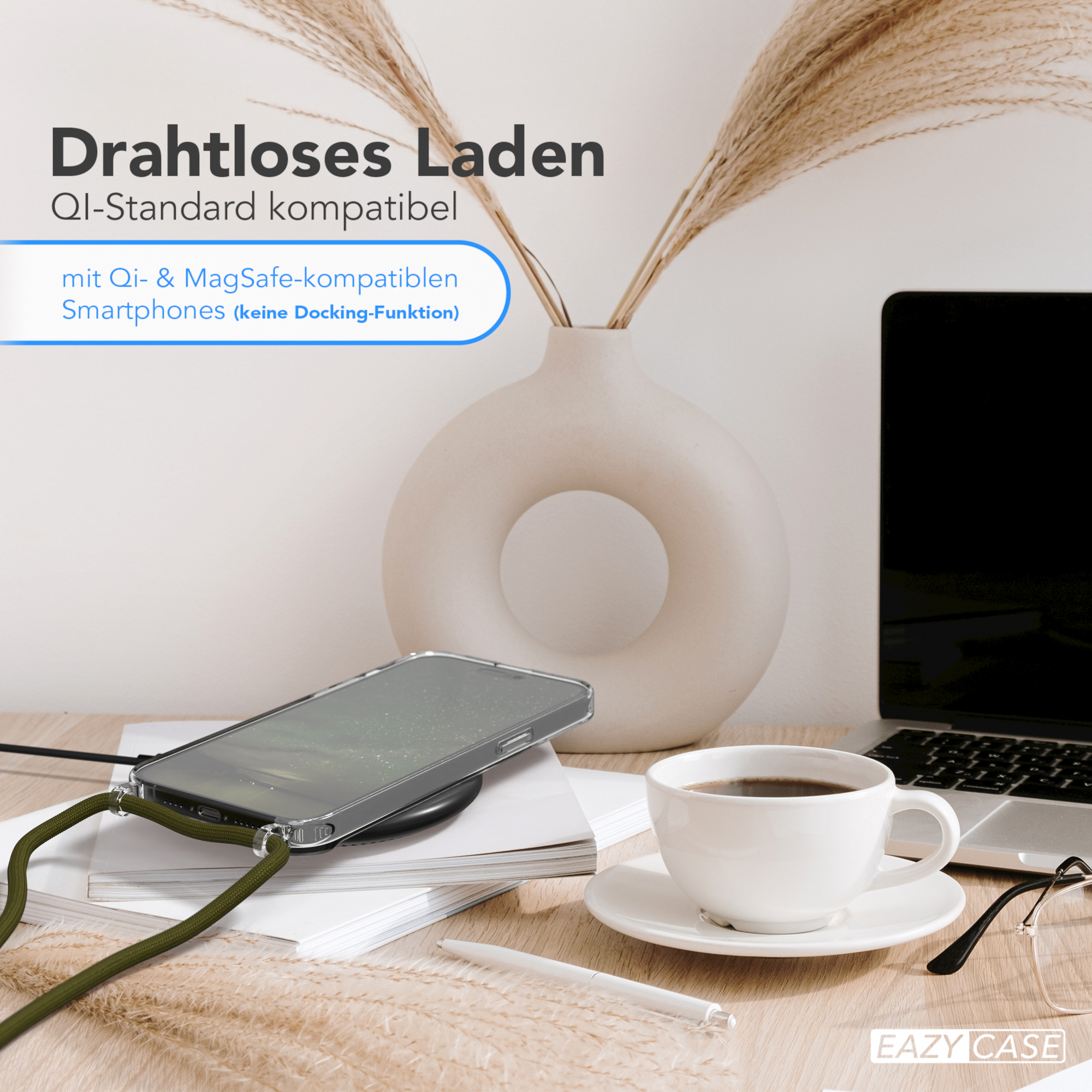 Telefon auf Ladegerät mit grünem Riemen. Daneben Vase, Kaffee und Laptop.