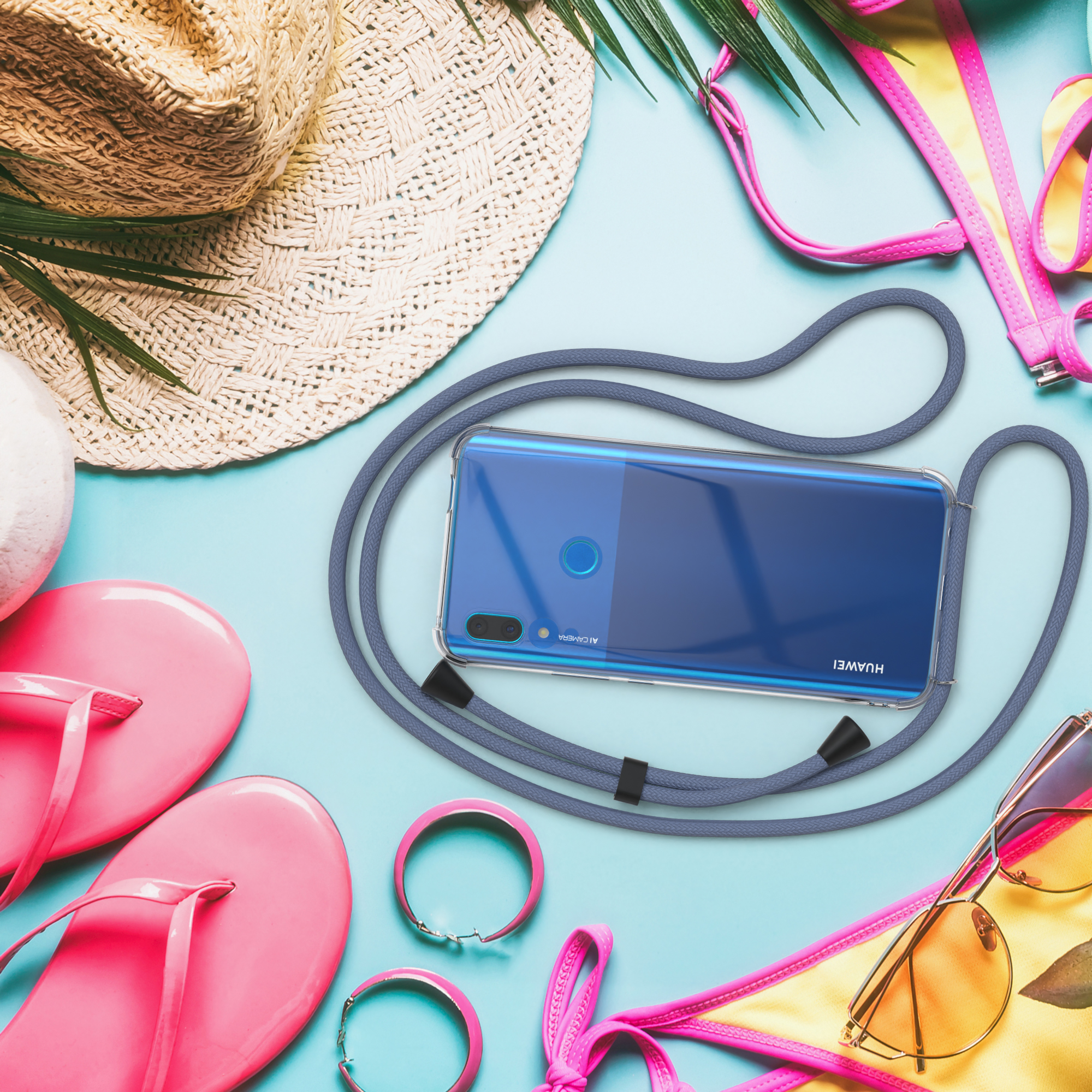 Ein Telefon in einer Hülle, das an einem Umhängeband hängt, mit Strandartikeln im Hintergrund.