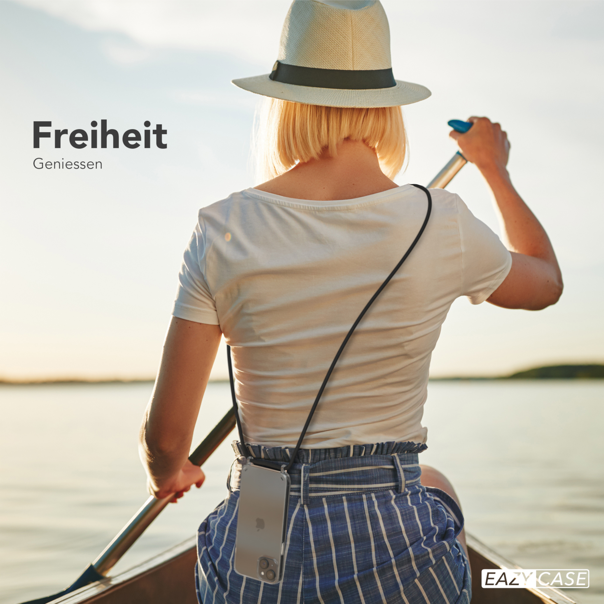 Frau in einem Boot, paddelnd. Sie trägt einen Hut und ein weißes Hemd, Telefon mit Hülle um den Hals.