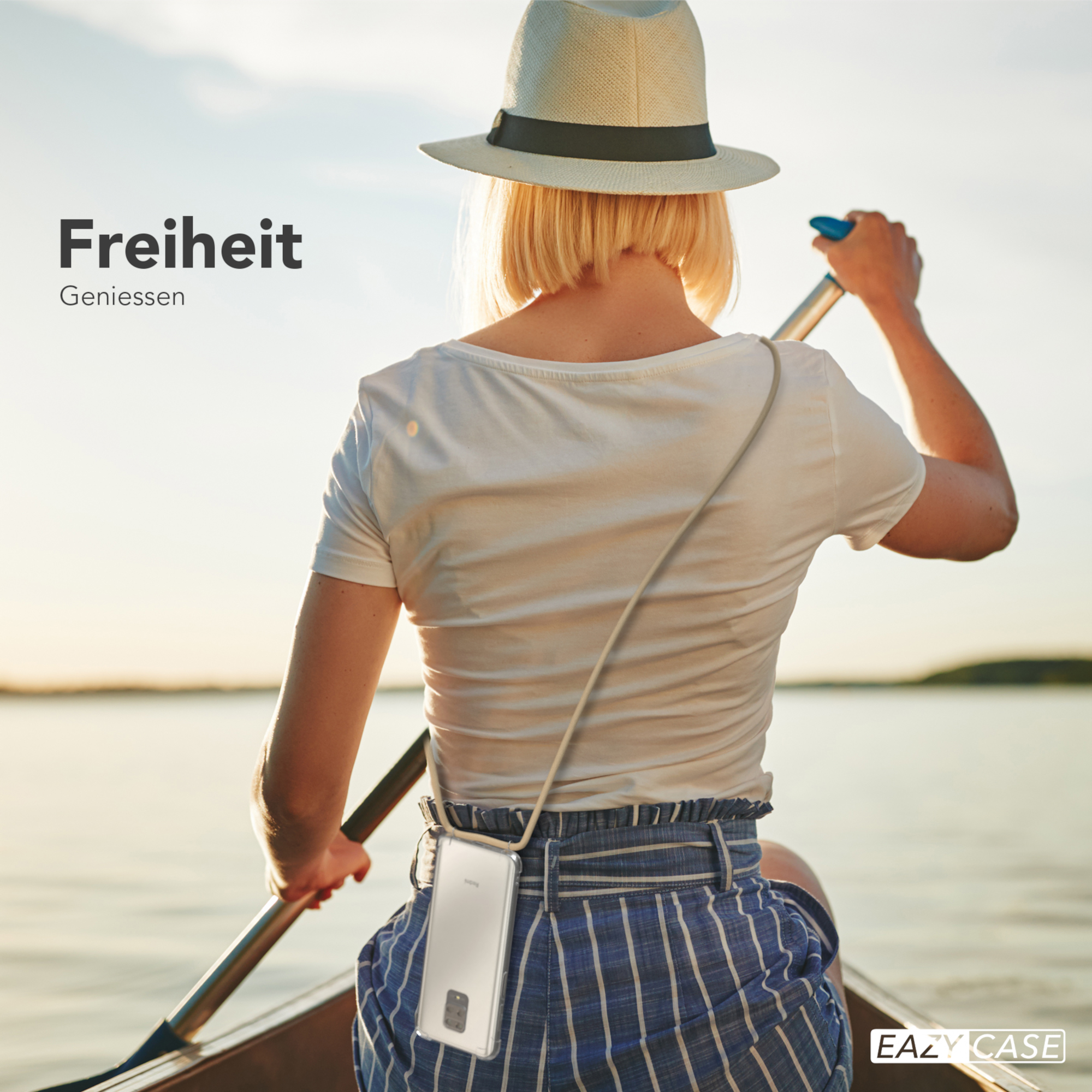 Eine Frau rudert ein Boot auf dem See. Sie trägt einen Hut, ein weißes Hemd und blau gestreifte Hosen.