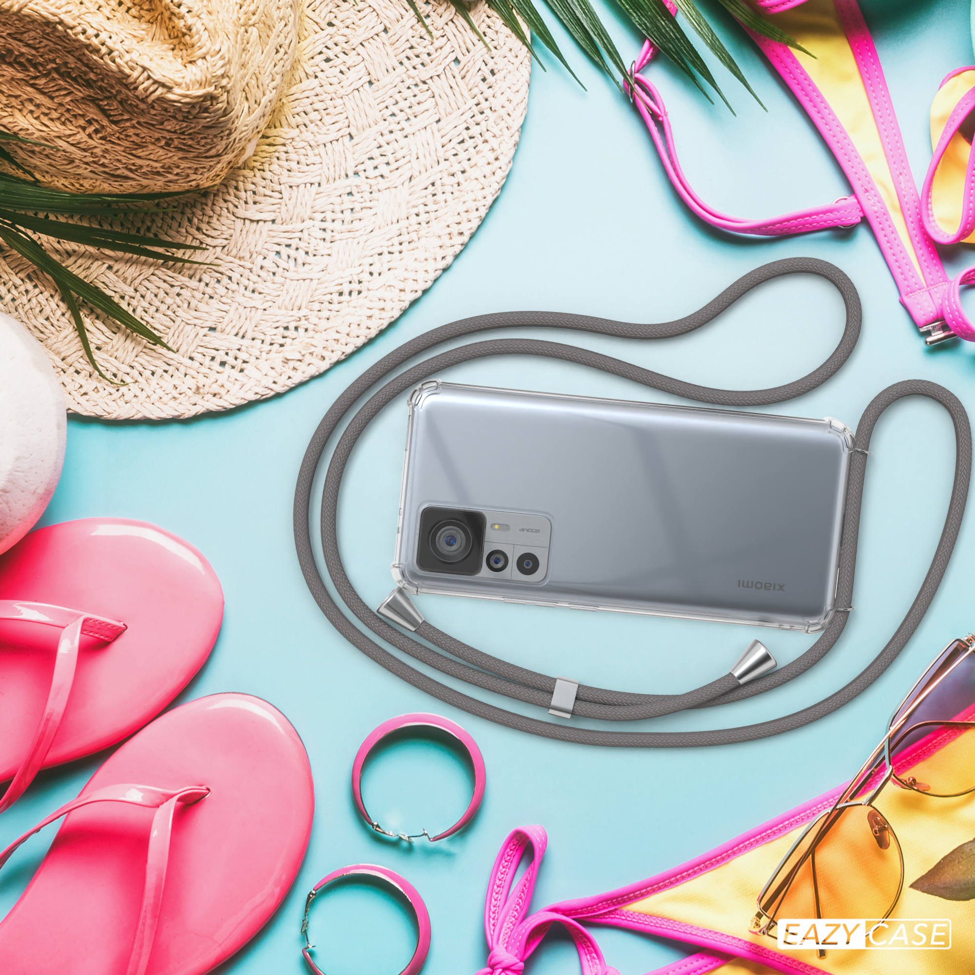 Telefon mit grauem Band, Sonnenbrille, Bikini, Hut und Armbänder auf blauem Hintergrund.