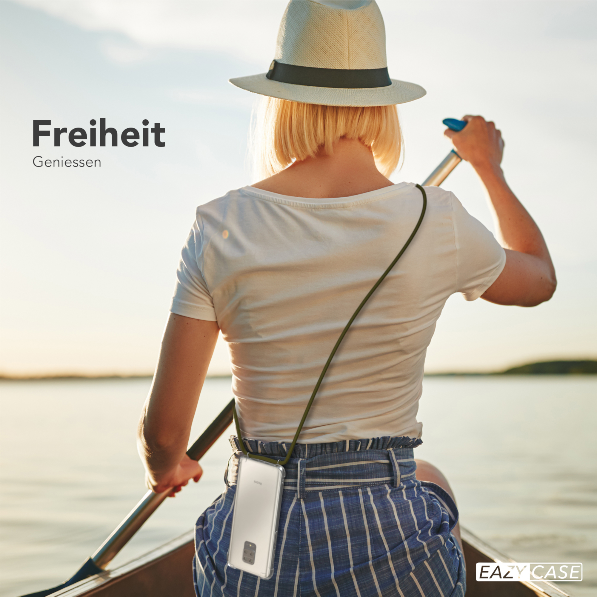 Eine Frau mit Hut rudert auf einem See. Ein Telefon hängt mit einem grünen Schlüsselband um ihren Hals.