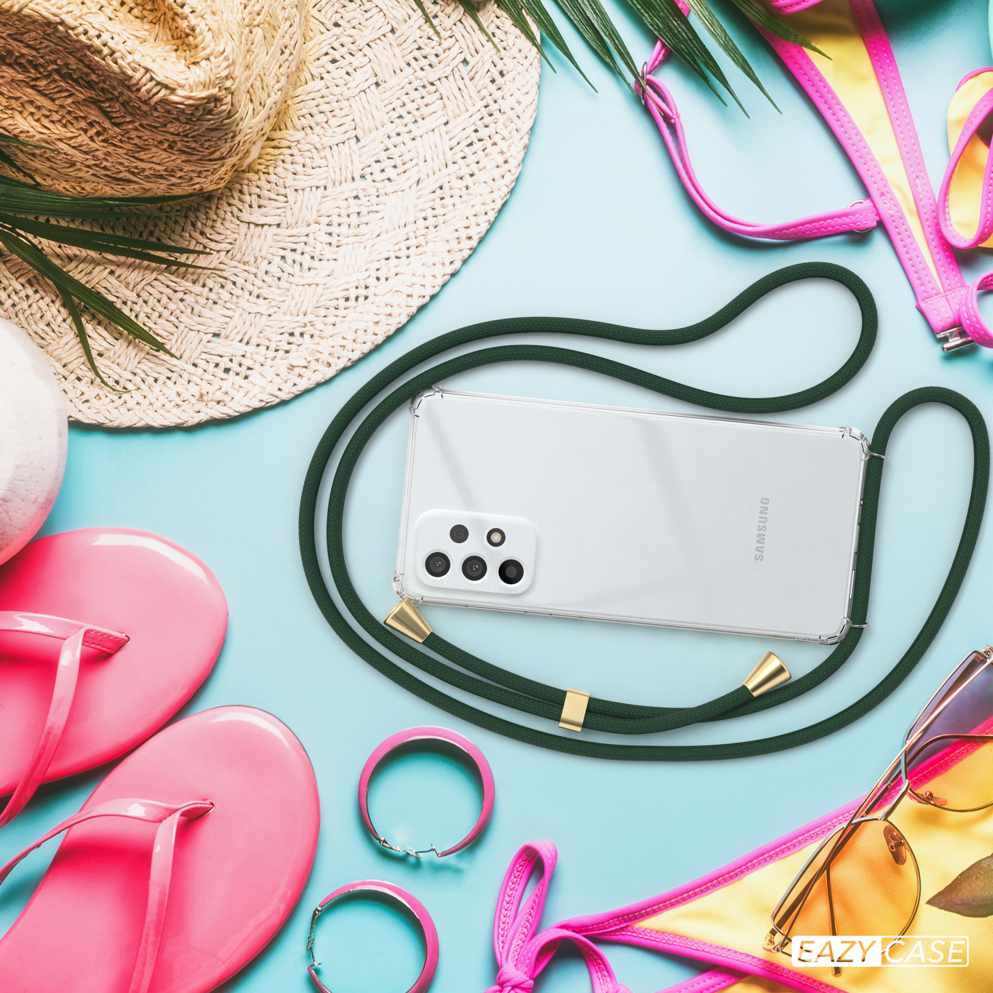 Ein Telefon mit grünem Riemen, Strandaccessoires auf blauem Hintergrund.