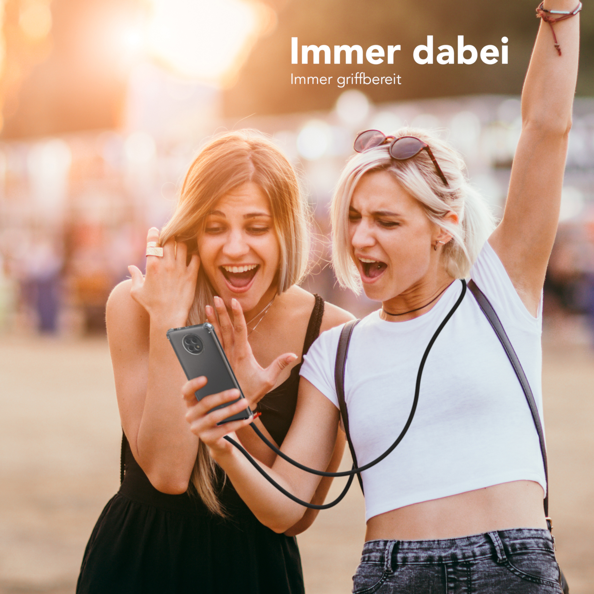 Zwei Frauen schauen auf ein Telefon, eine mit Kabel. Text: Immer dabei.