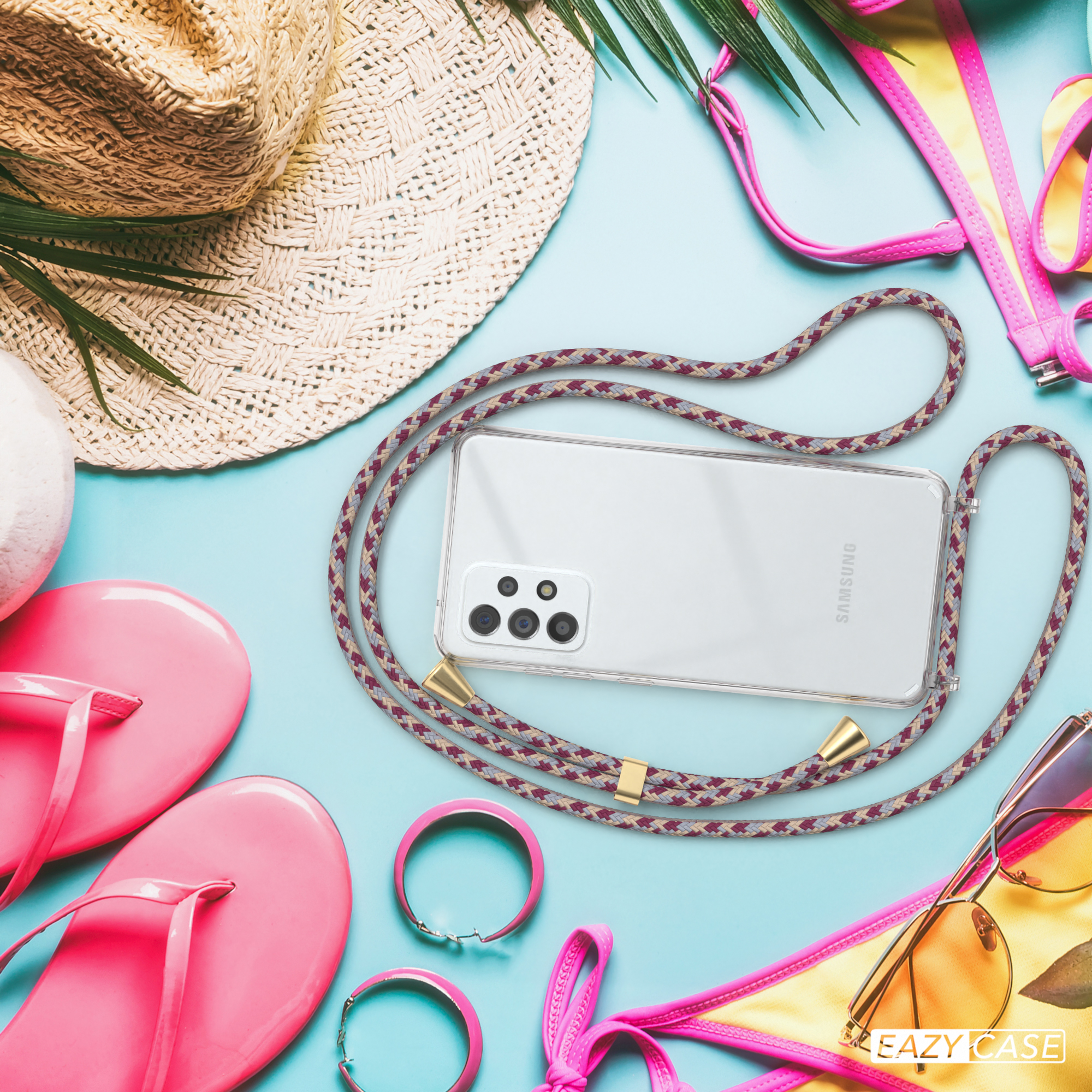 Telefon mit Riemen auf einem Tisch. Es gibt Sonnenbrillen, einen Hut und andere Strandartikel.