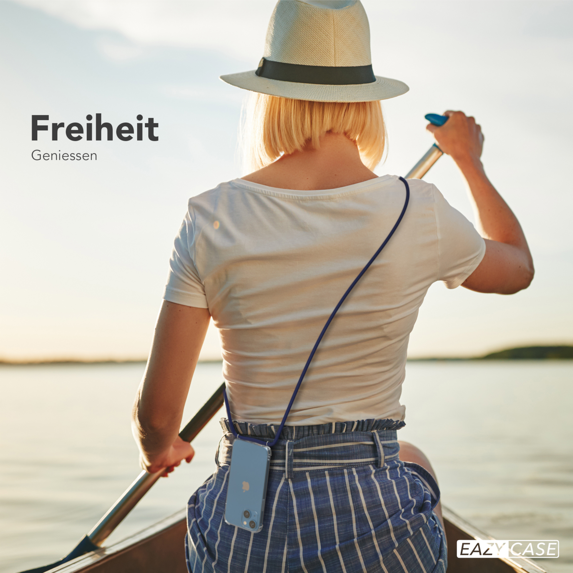 Eine Frau rudert in einem Boot auf einem See, mit Hut. Eine Handyhülle mit Riemen ist sichtbar, am Telefon befestigt.