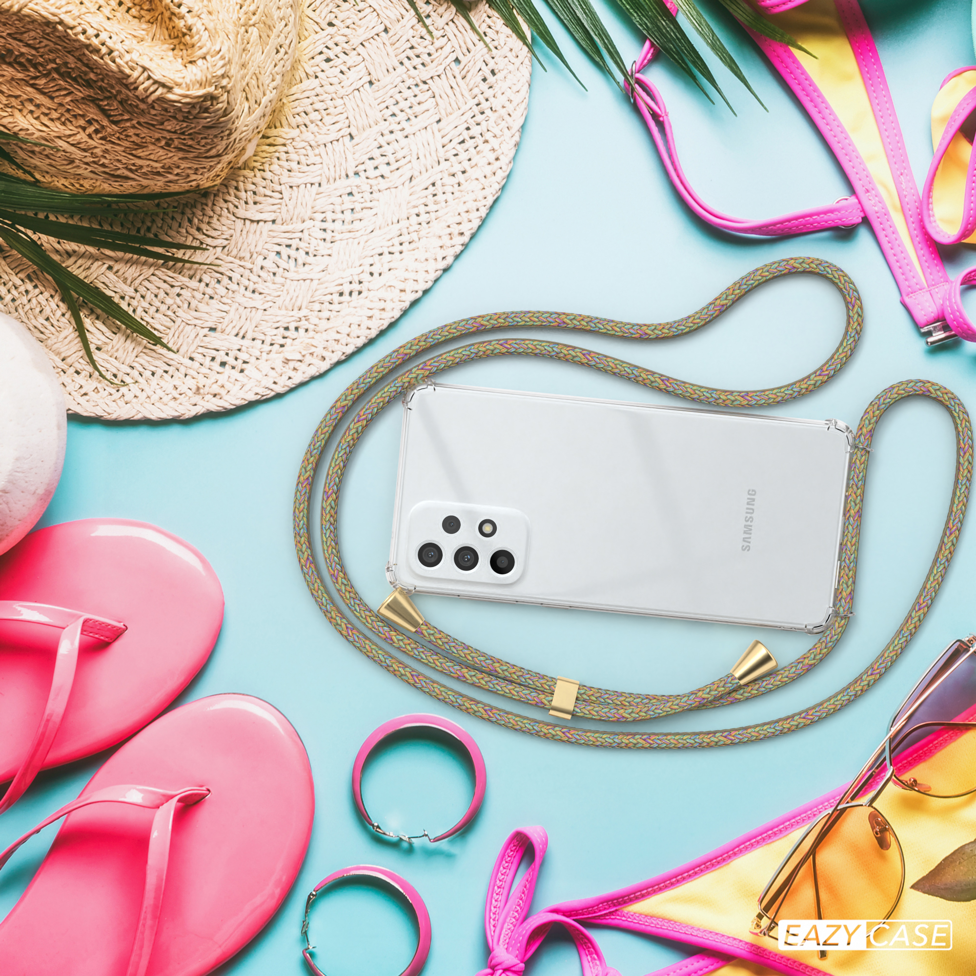 Telefon mit Hülle am Strand. Ein Hut, eine Sonnenbrille und anderes Strandzubehör liegen darum herum.
