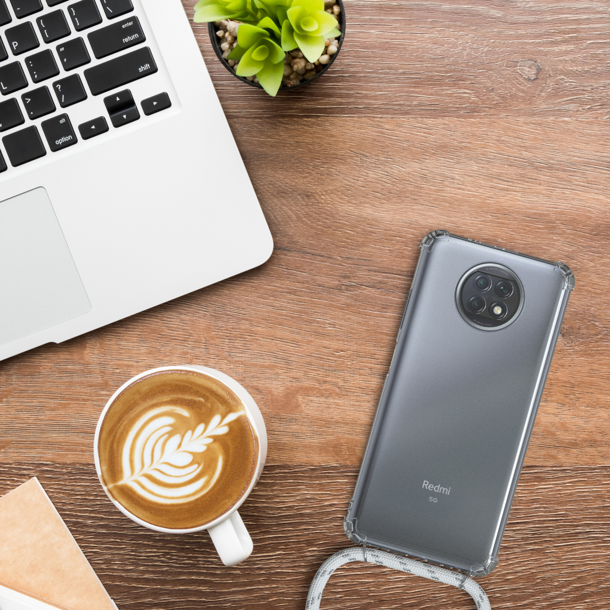 Laptop, Kaffee und Telefon in einer Hülle auf einem Holzschreibtisch. Eine Pflanze ist ebenfalls zu sehen.