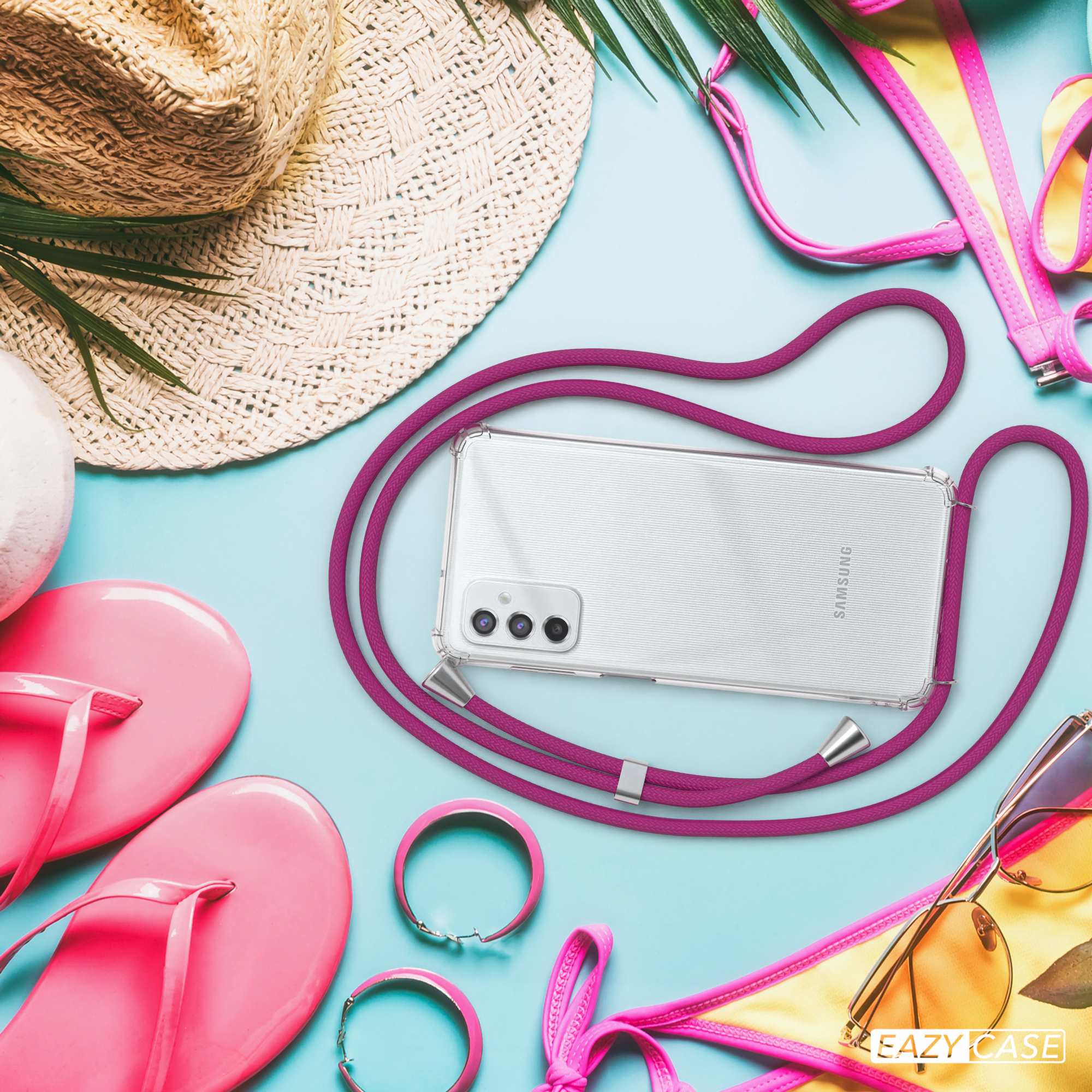 Telefon auf Tisch mit Strandartikeln. Pinker Riemen ist befestigt. Sonnenbrille, Hut und Bikini-Set sind sichtbar.
