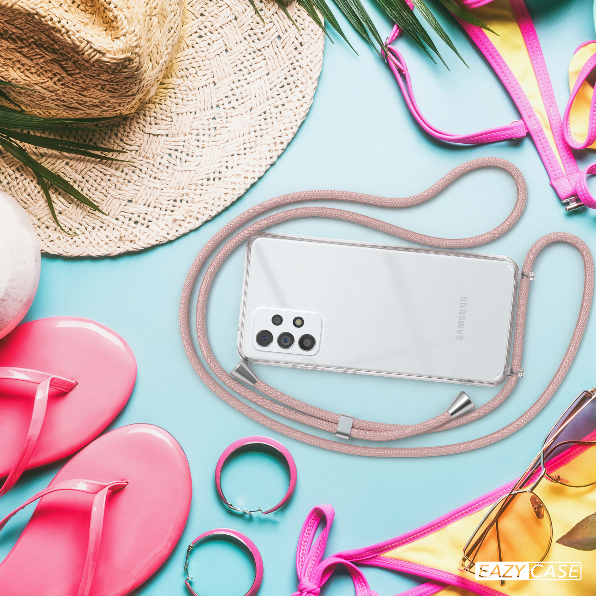 Telefon mit rosa Lanyard, Sonnenbrille, Hut und Flip-Flops liegen auf blauer Oberfläche und schaffen Strandatmosphäre.