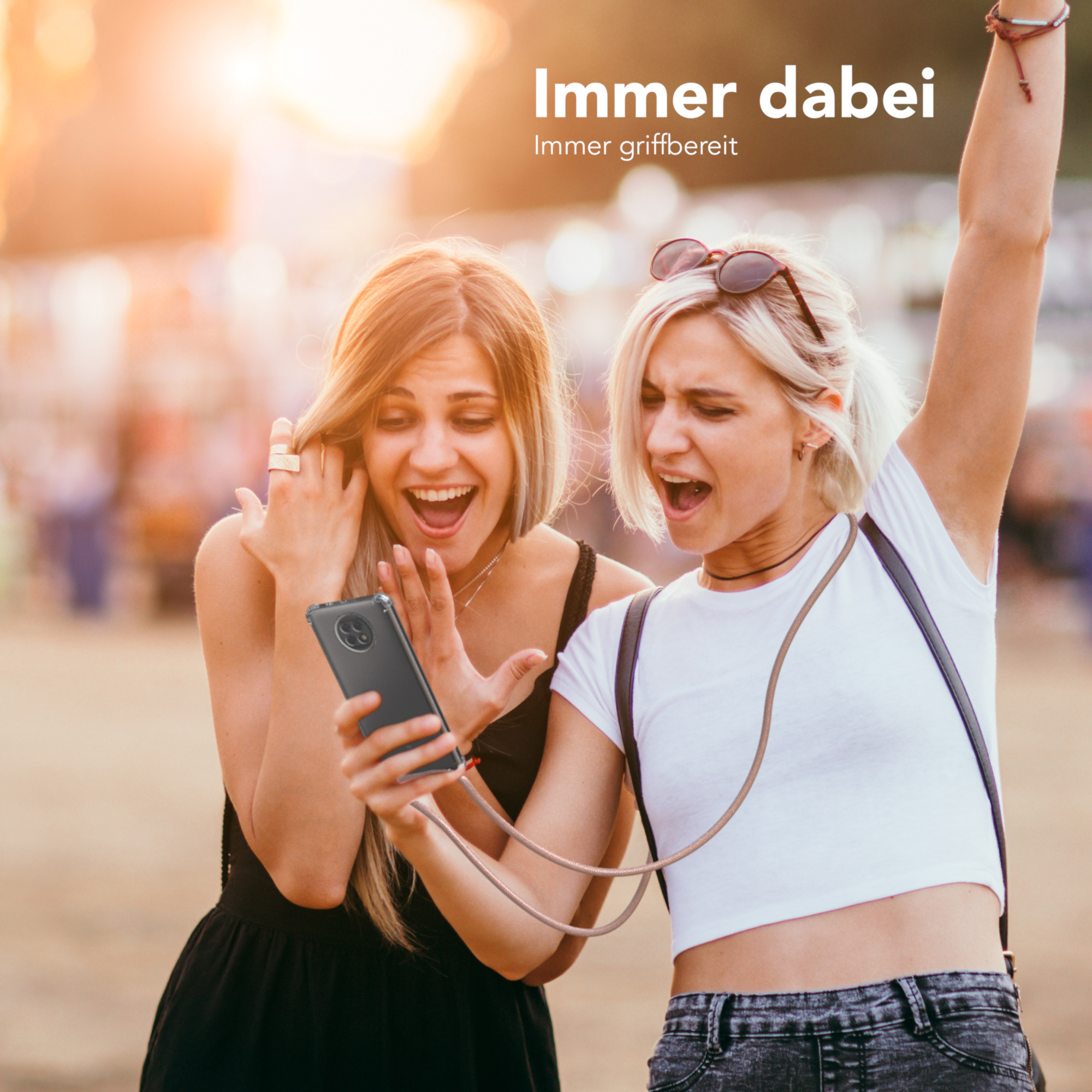 Zwei Frauen schauen auf ein Telefon, eine hält es, beide aufgeregt. Hintergrund ist verschwommen.