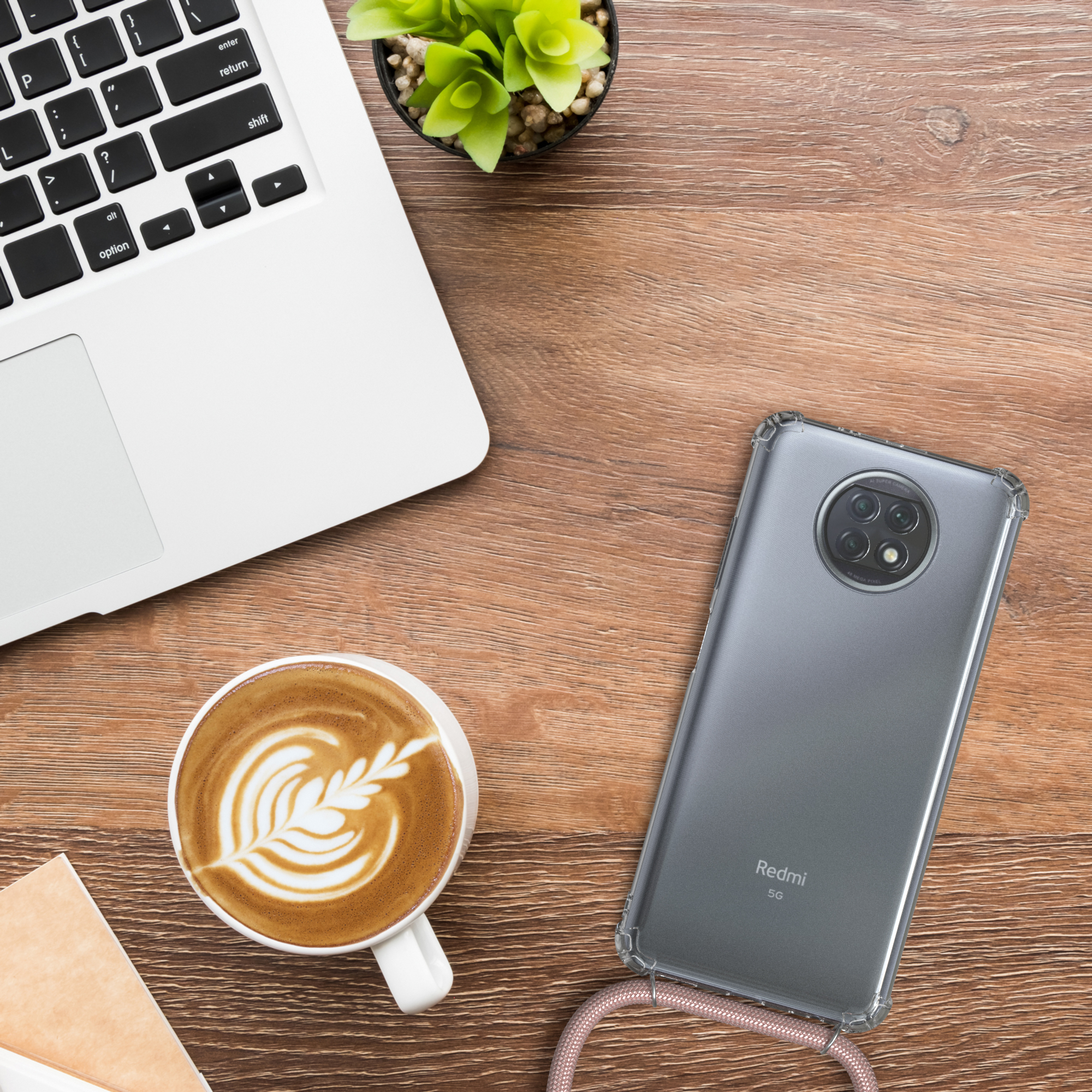 Ein Laptop, Kaffee und Telefon liegen auf einem Holztisch. Das Telefon hat eine Hülle.