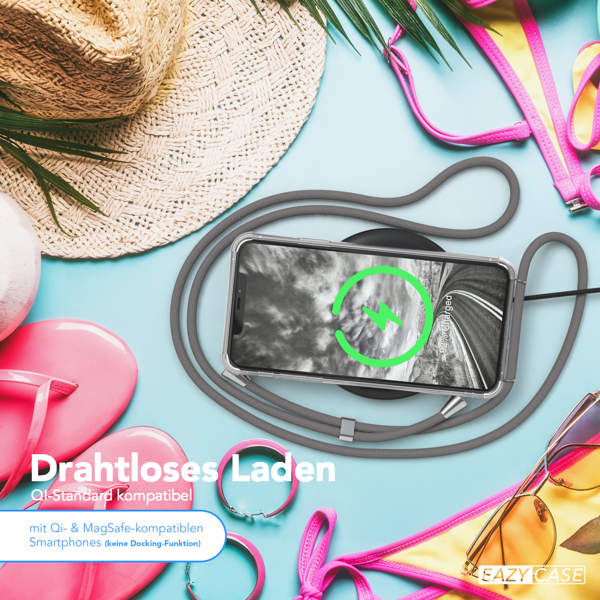Ein Telefon wird kabellos auf einem Pad geladen. Strandartikel wie Hut, Sonnenbrille und rosa Sandalen sind umgeben.