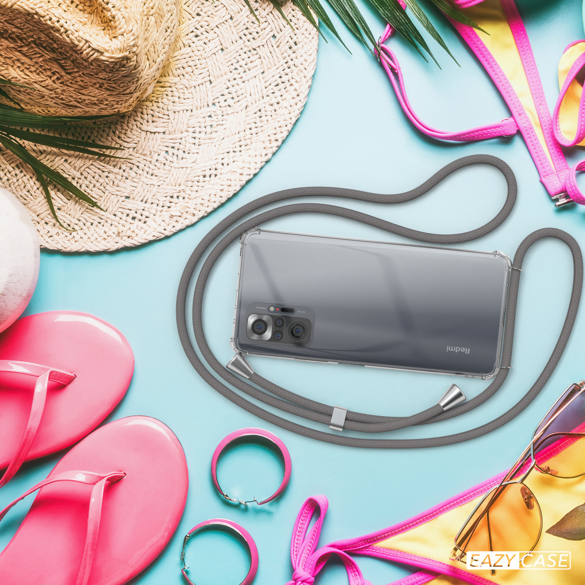 Telefon mit Lanyard, Sonnenbrille, Flip-Flops, Hut und Armbändern auf blauem Untergrund.