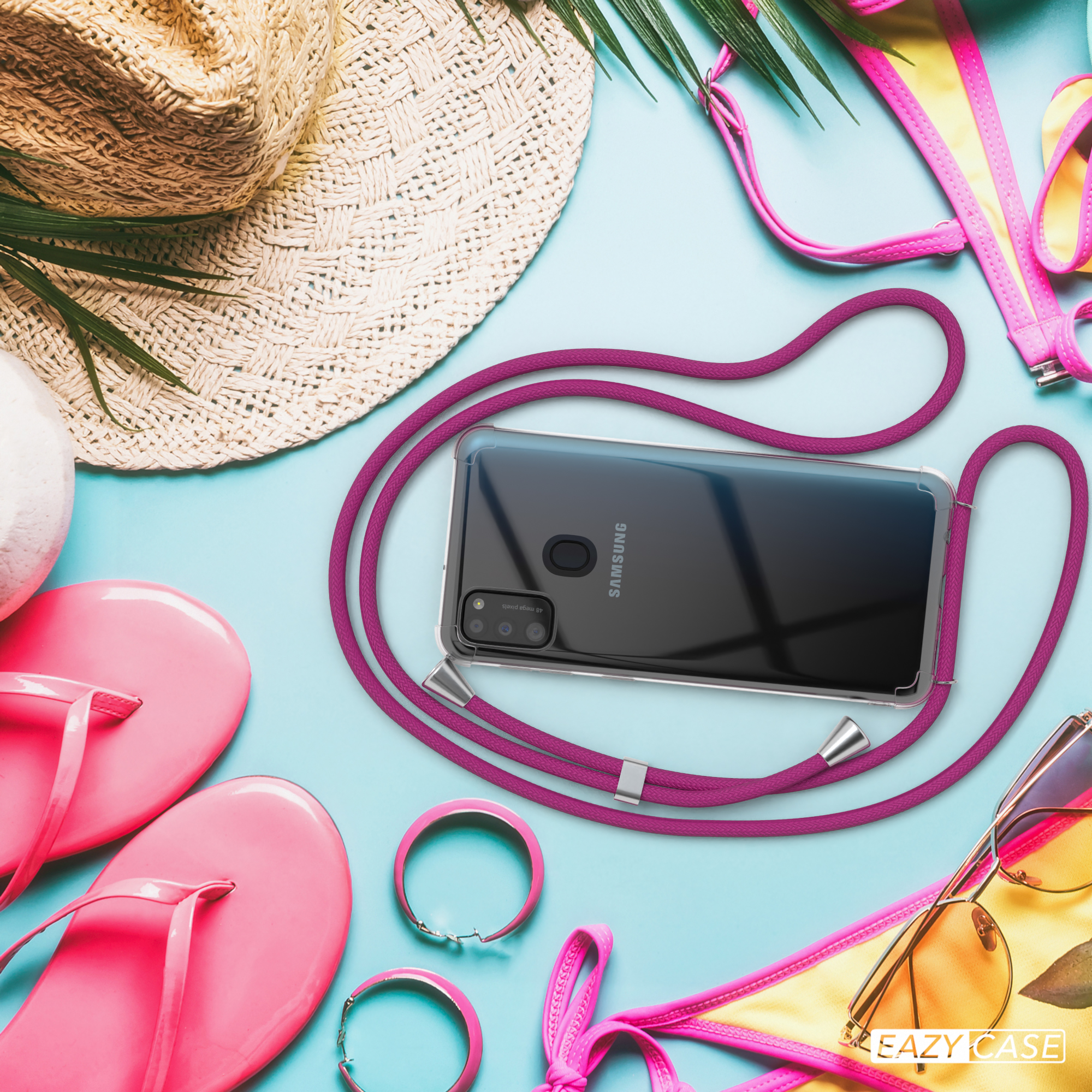 Handyhülle mit lila Kordel, umgeben von Strandutensilien: Strohhut, Sonnenbrille und pinkfarbene Flip-Flops.