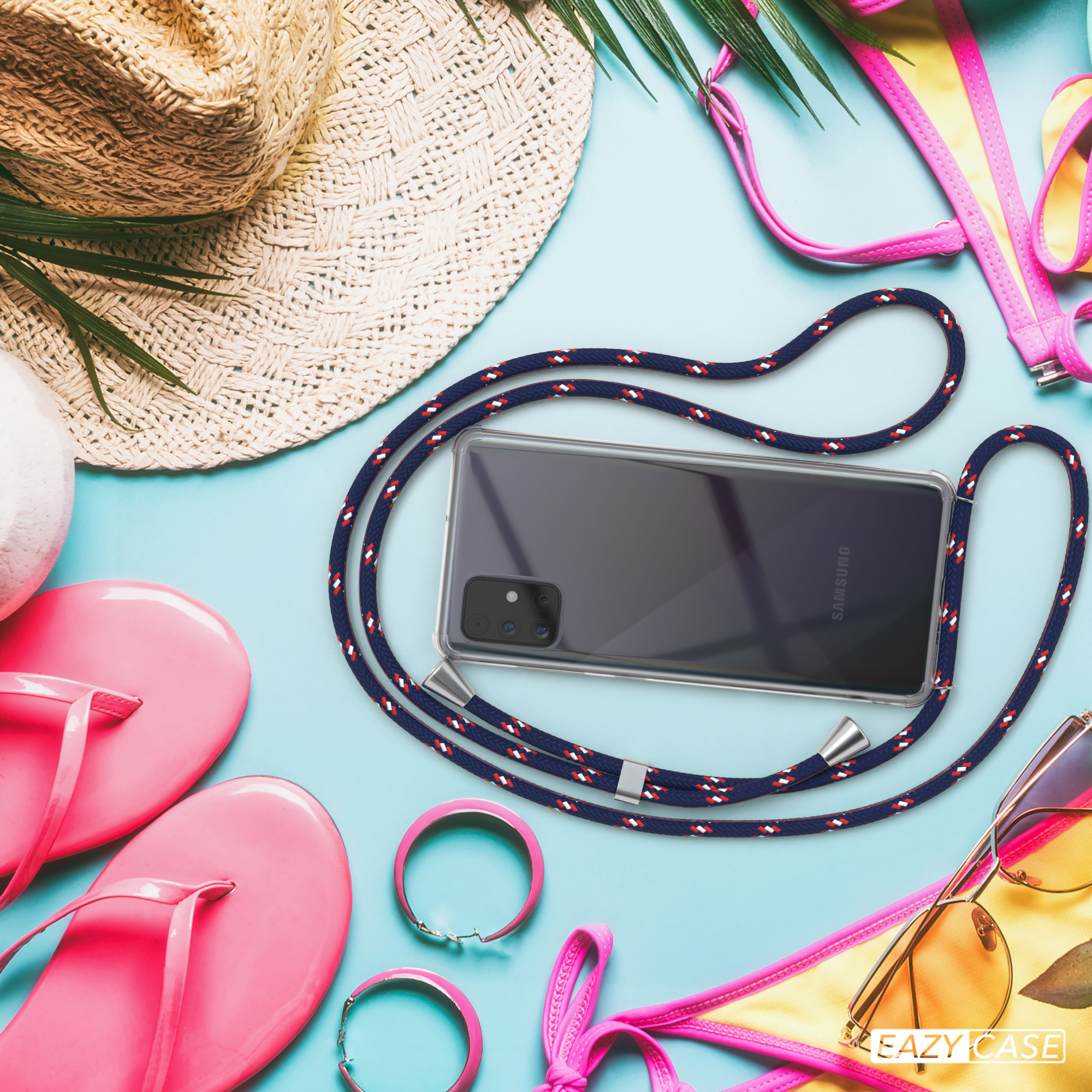 Telefon mit klarer Hülle und Ladepad auf blauer Oberfläche mit Strandartikeln.