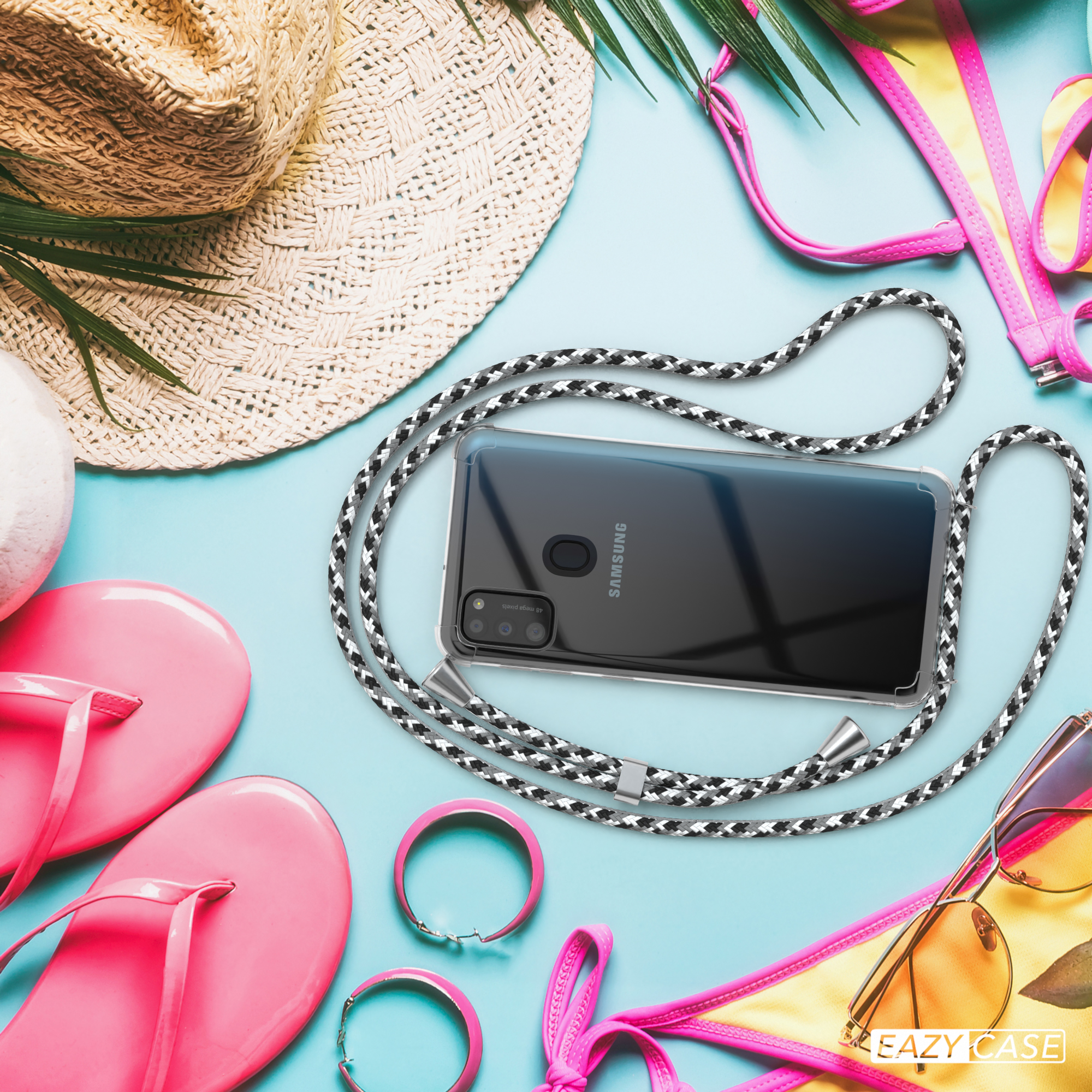 Telefon mit Hülle und schwarz-weißem Seil, umgeben von Strandutensilien wie Hut und Sonnenbrille.