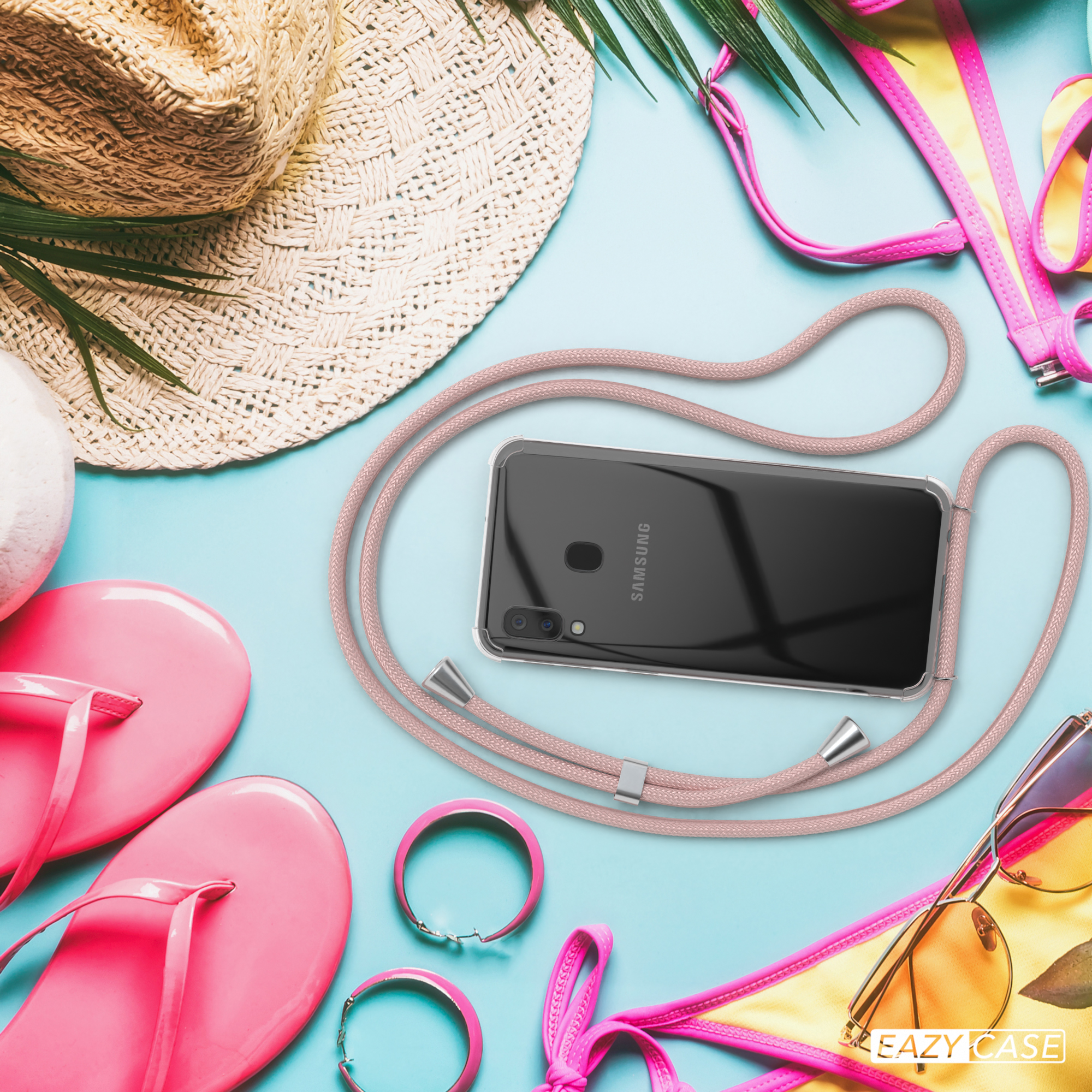 Ein Telefon mit rosa Seil am Strand mit rosa Flip-Flops, Hut und Sonnenbrille.