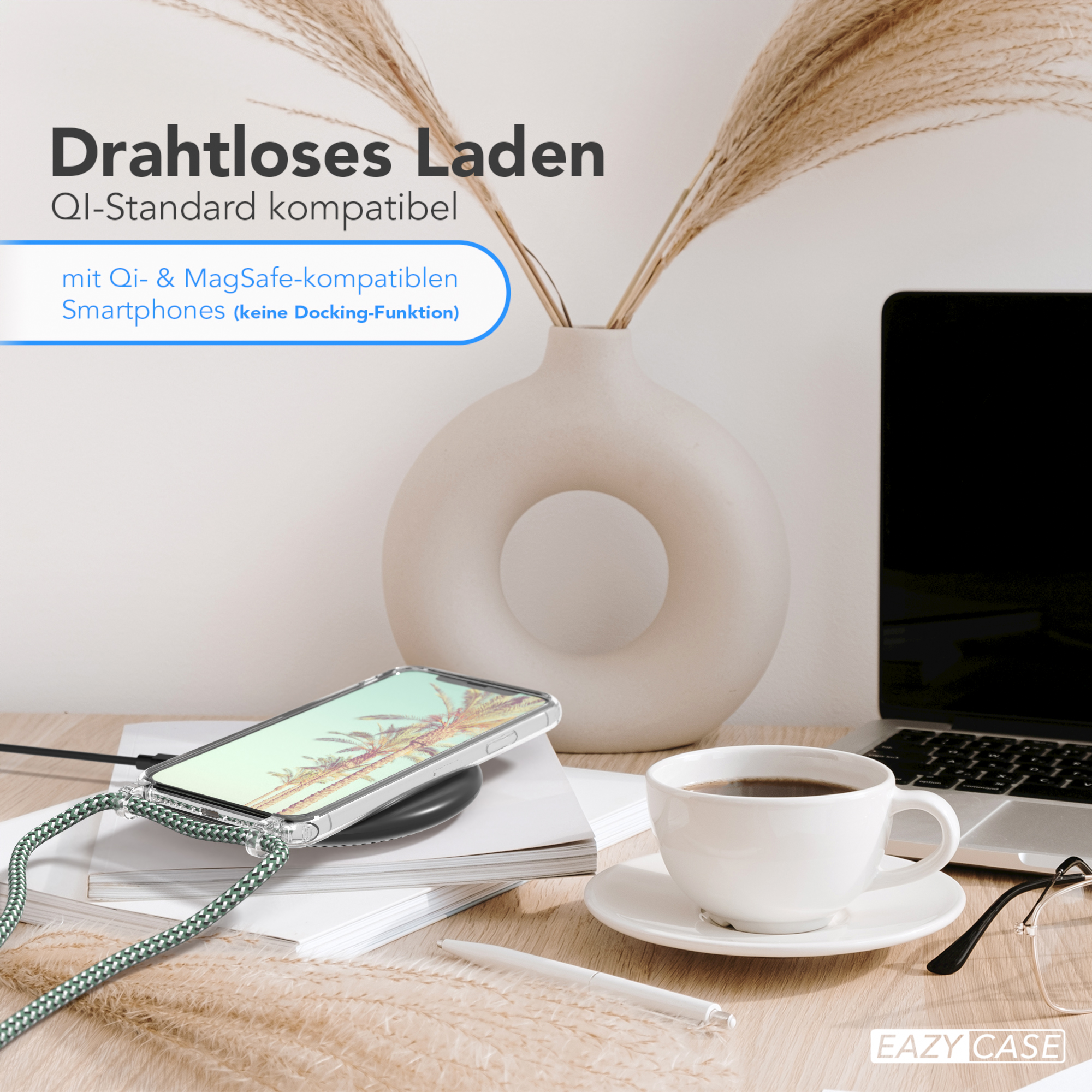 Telefon auf kabellosem Ladegerät, Kaffee, Stift, Vase und Laptop auf einem Holztisch.