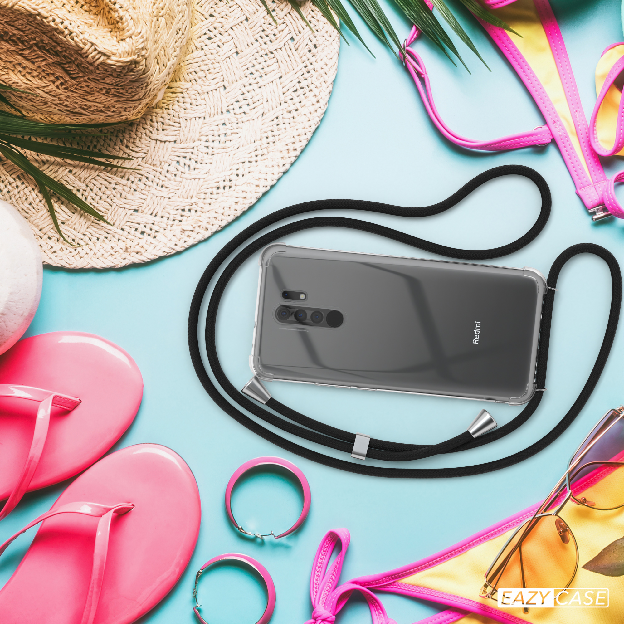 Telefon mit klarer Hülle und schwarzem Band, neben Sonnenbrille, Hut und rosa Flip-Flops.