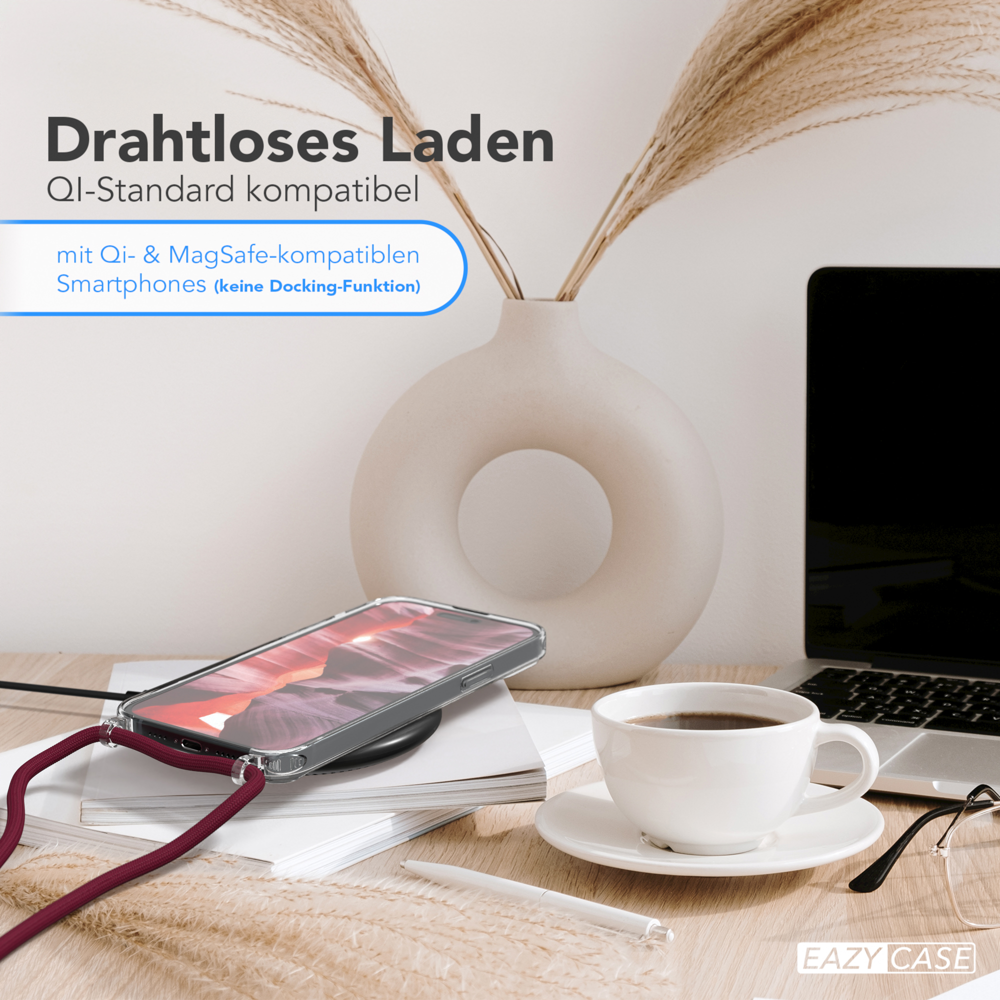 Telefon auf kabellosem Ladegerät auf dem Schreibtisch. Kaffeetasse, Vase mit Pflanzen und Brille vorhanden.