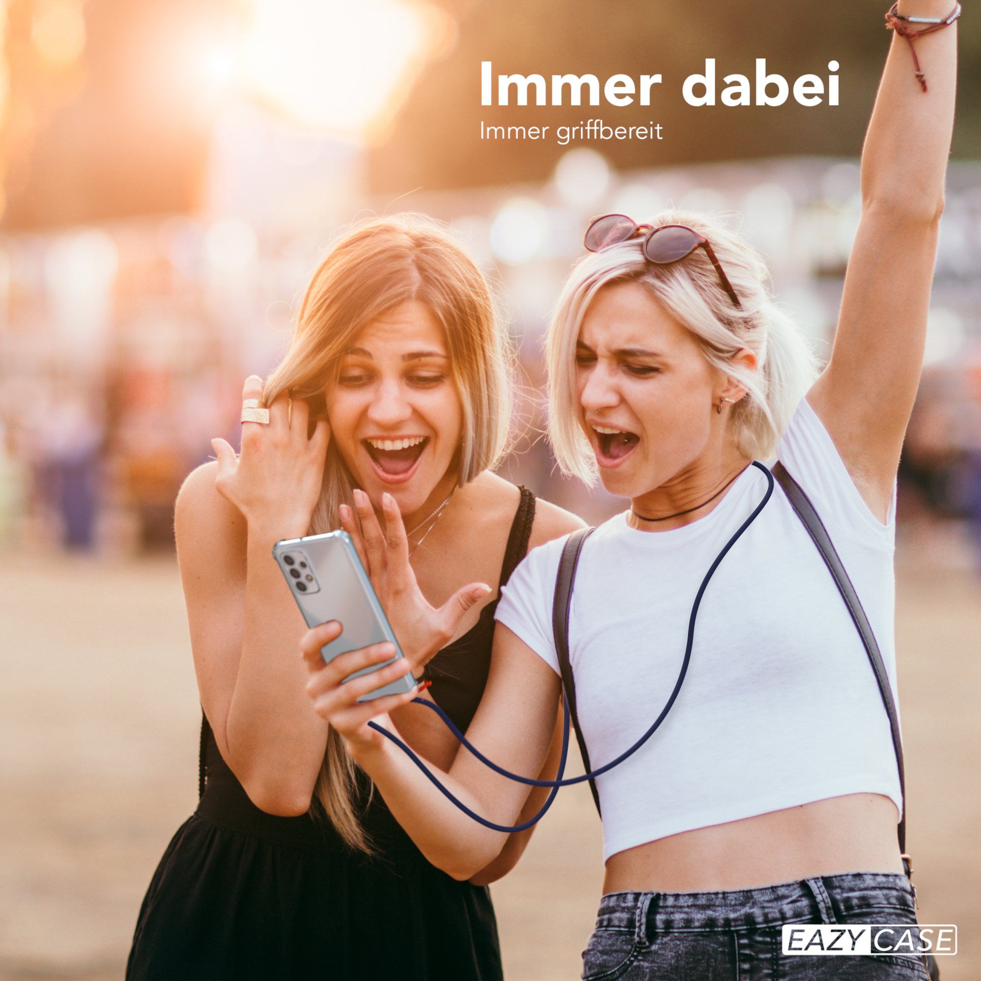 Zwei Frauen schauen auf ein Telefon, aufgeregt. Text: Immer dabei, Immer griffbereit. Handyhülle ist befestigt.