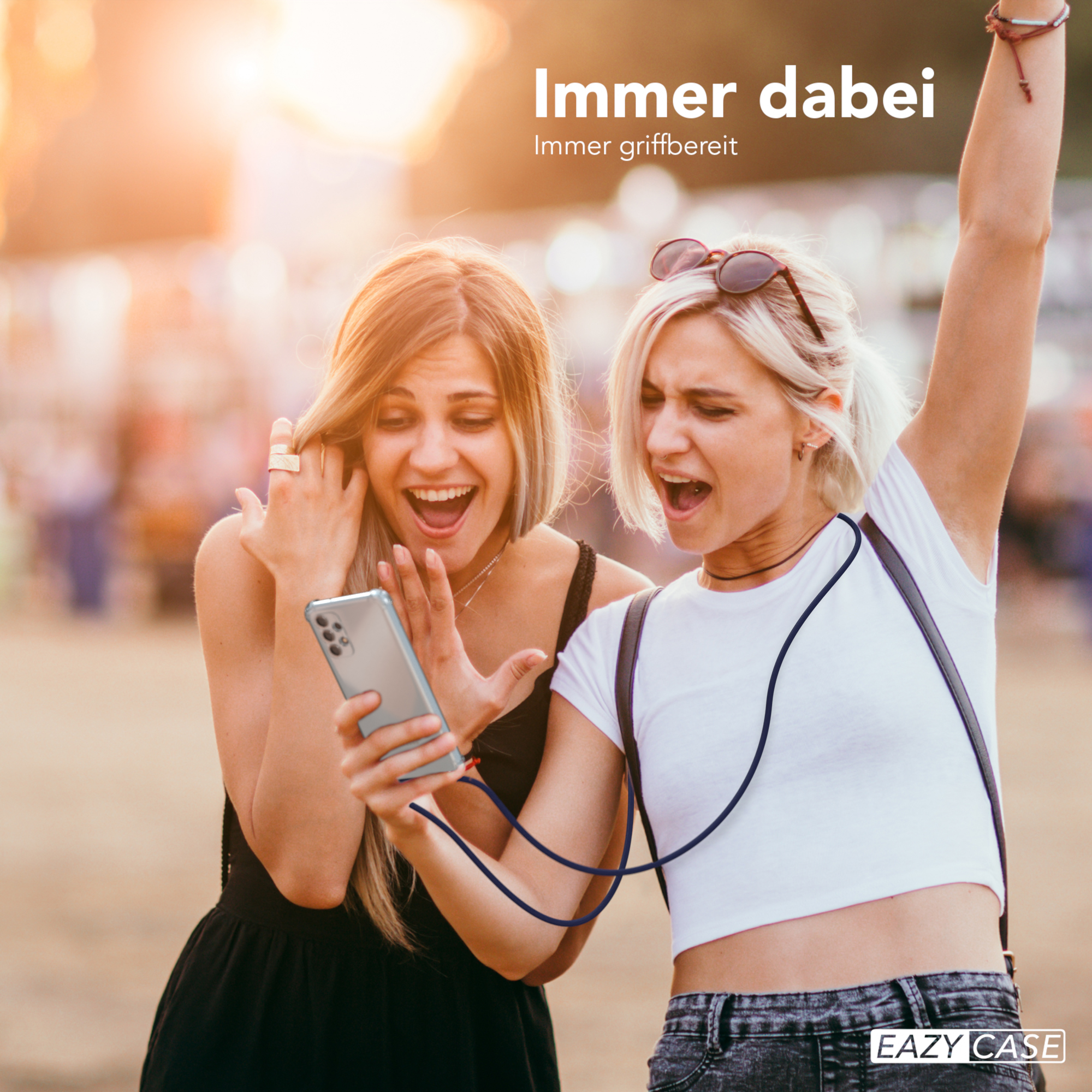 Zwei Frauen schauen auf ein Handy. Eine hält das Handy mit einem Umhängeband.