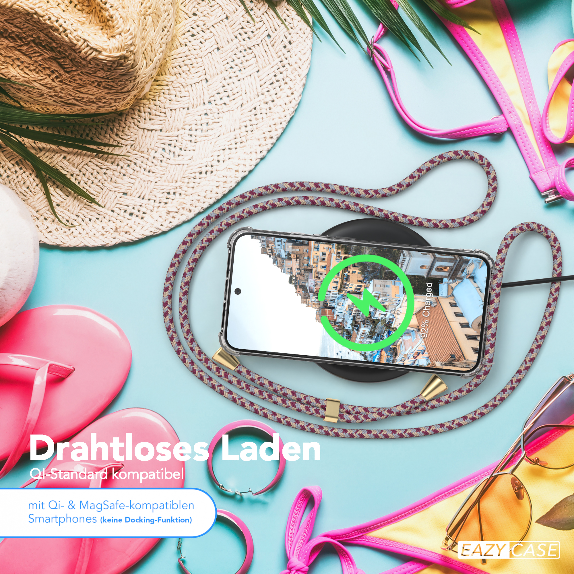 Telefon auf Ladegerät mit Kordel, umgeben von Accessoires. Strandthema.