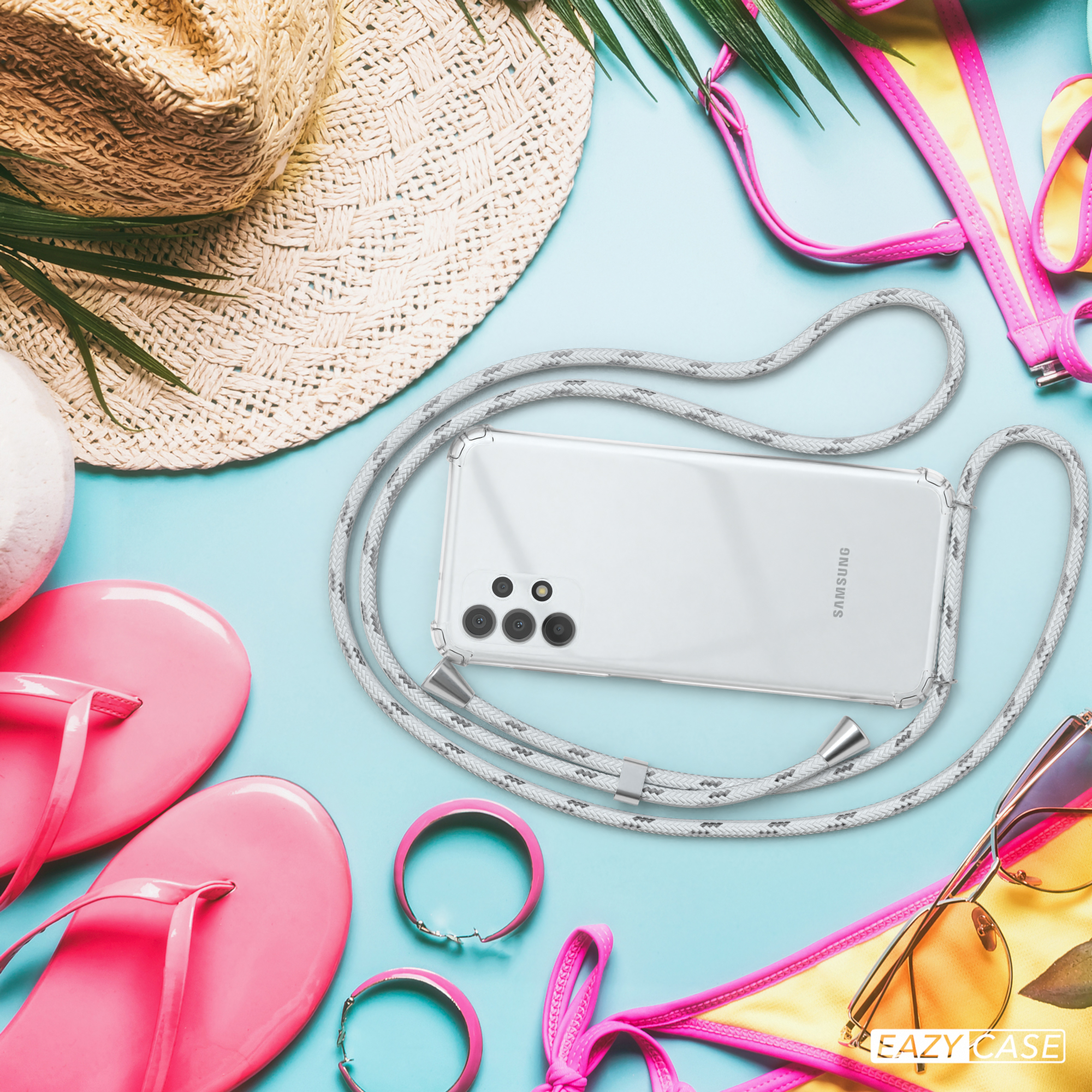 Telefon mit Lanyard auf blauem Untergrund mit Strandutensilien: Hut, Sonnenbrille, rosa Flip-Flops und Zubehör.