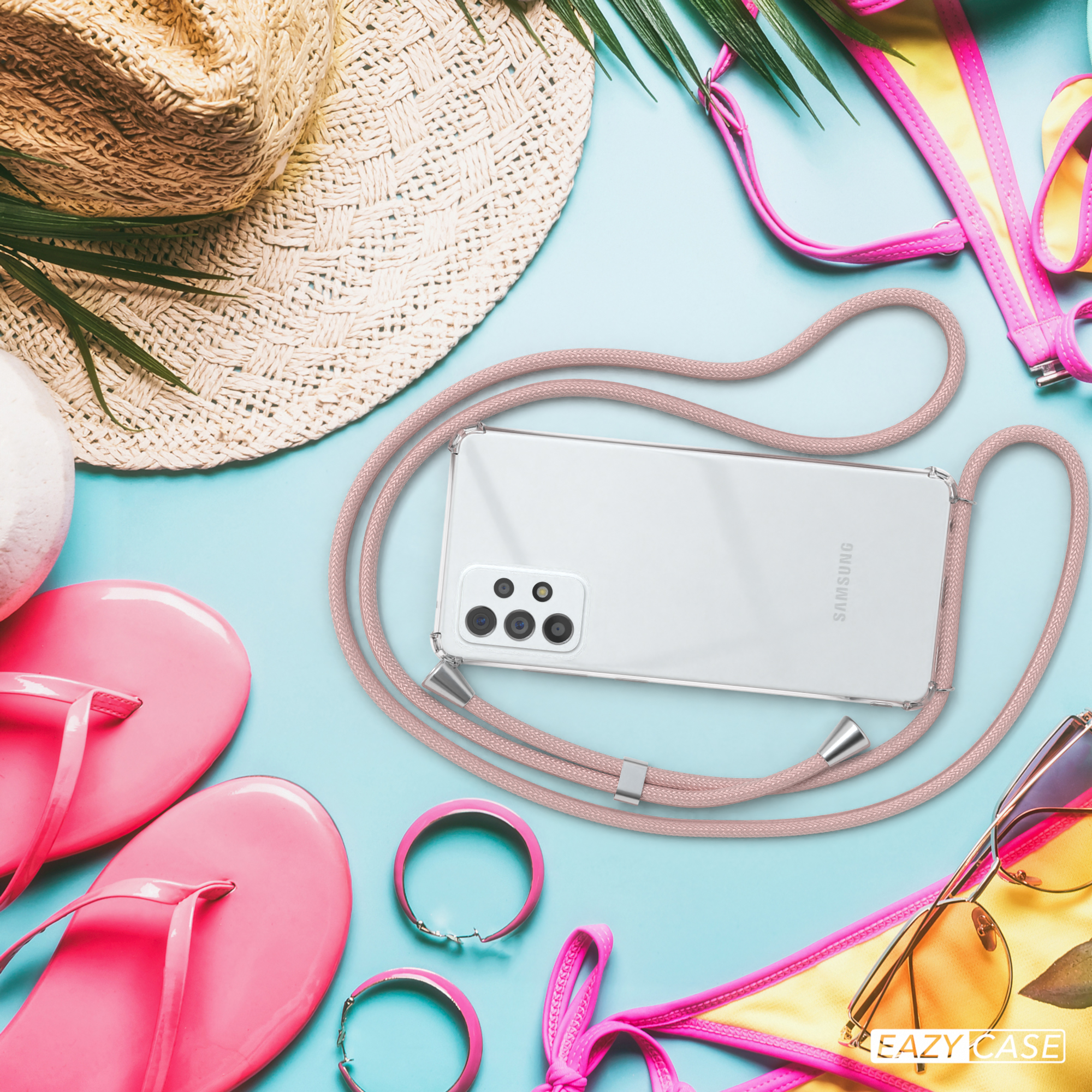 Telefon mit pinkem Seil auf blauem Untergrund mit Sommeraccessoires.