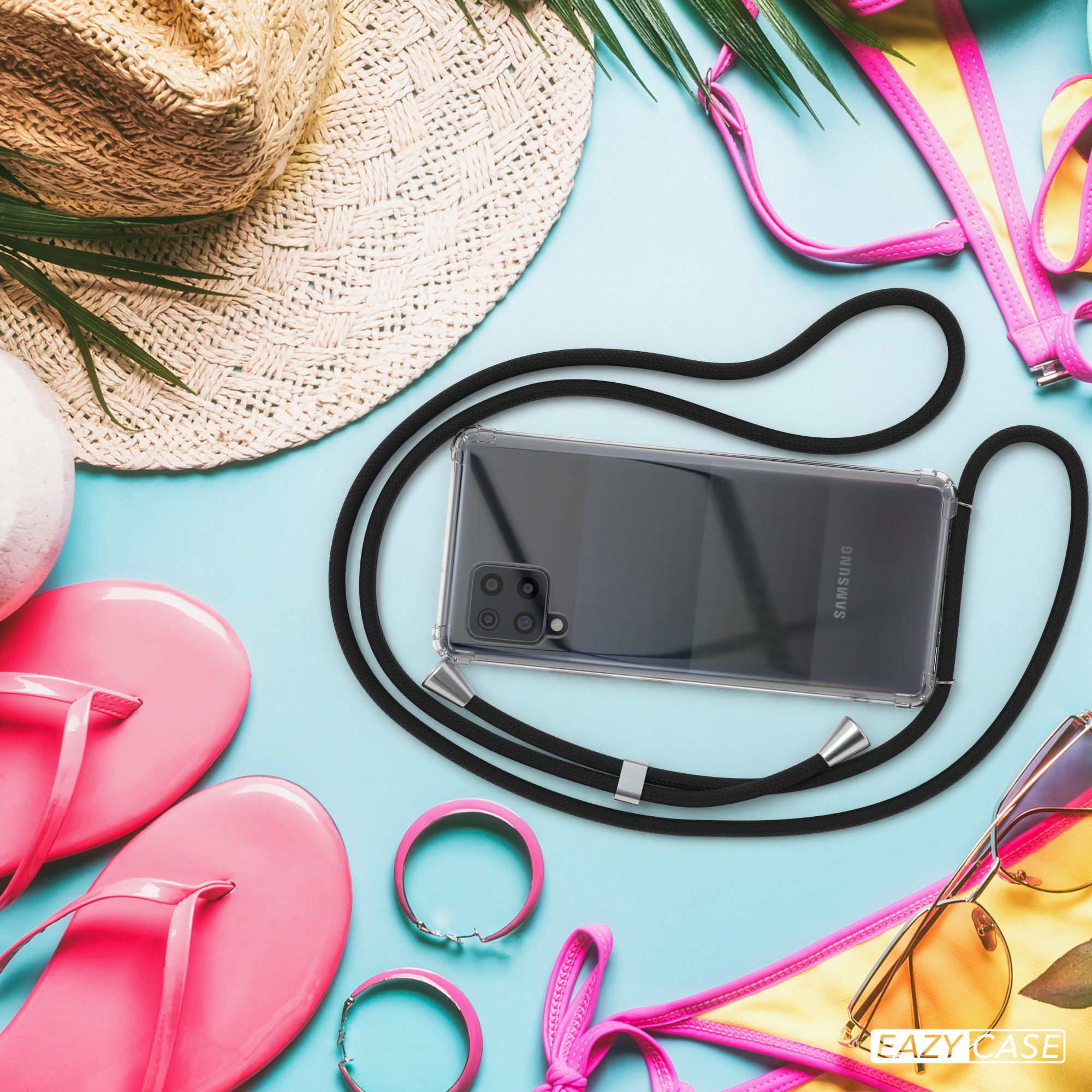 Telefon mit Hülle und Kordel auf blauem Untergrund mit Zubehör. Strandartikel, Sonnenbrille und Hut.