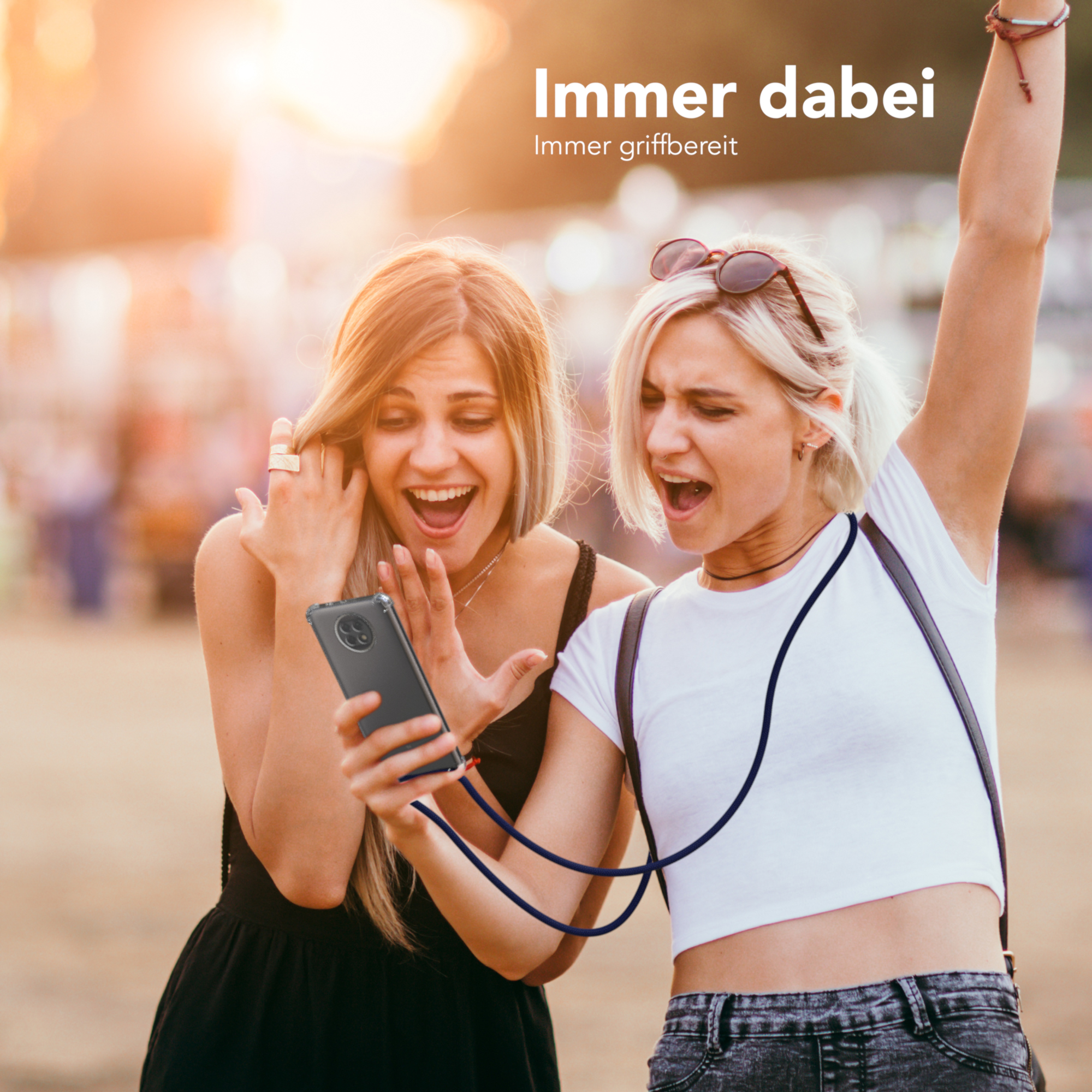 Zwei Frauen schauen auf ein Telefon, aufgeregt. Eine Frau hält das Telefon, beide lächeln.