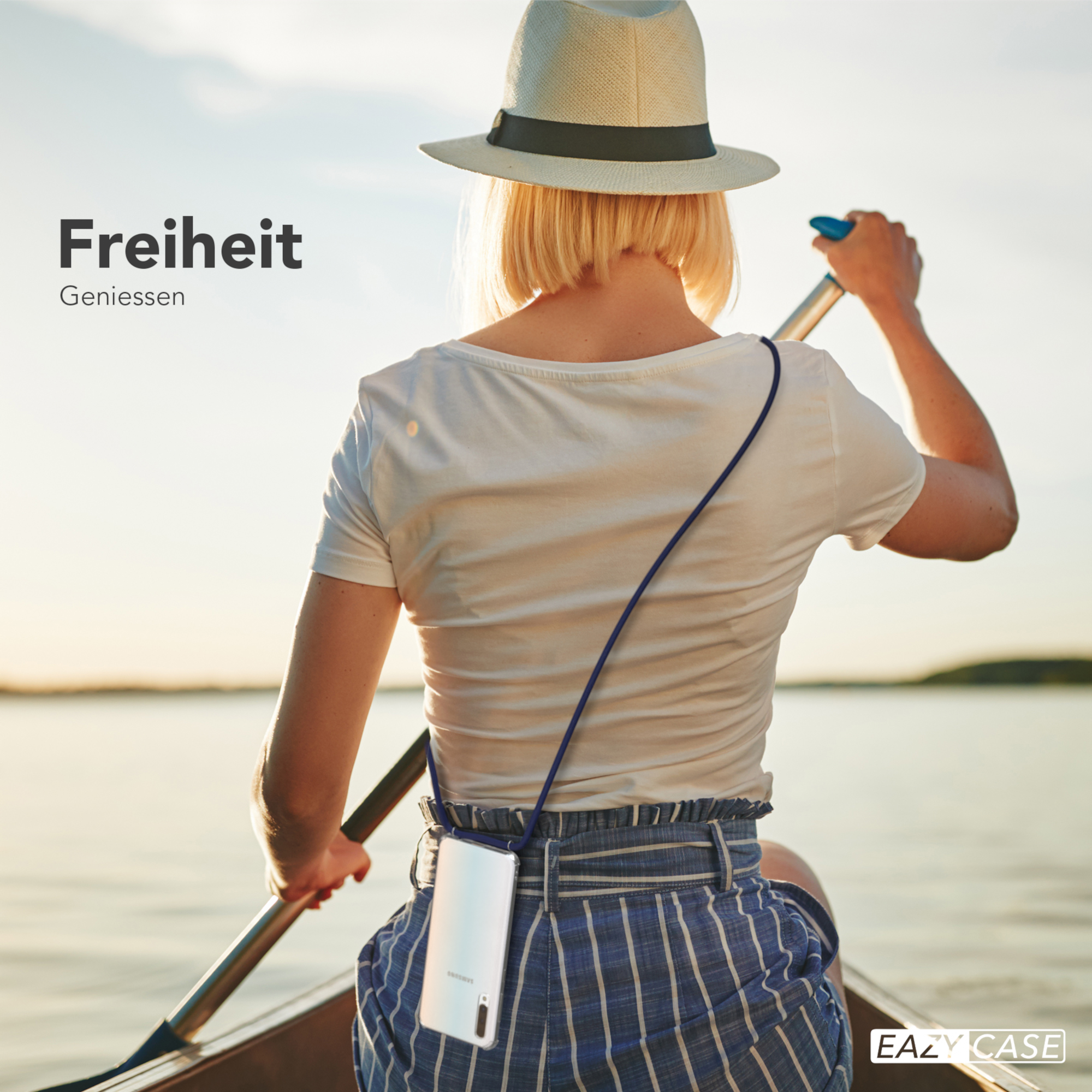 Frau paddelt im Boot auf dem See. Sie trägt einen Hut und eine Handyhülle um den Hals.