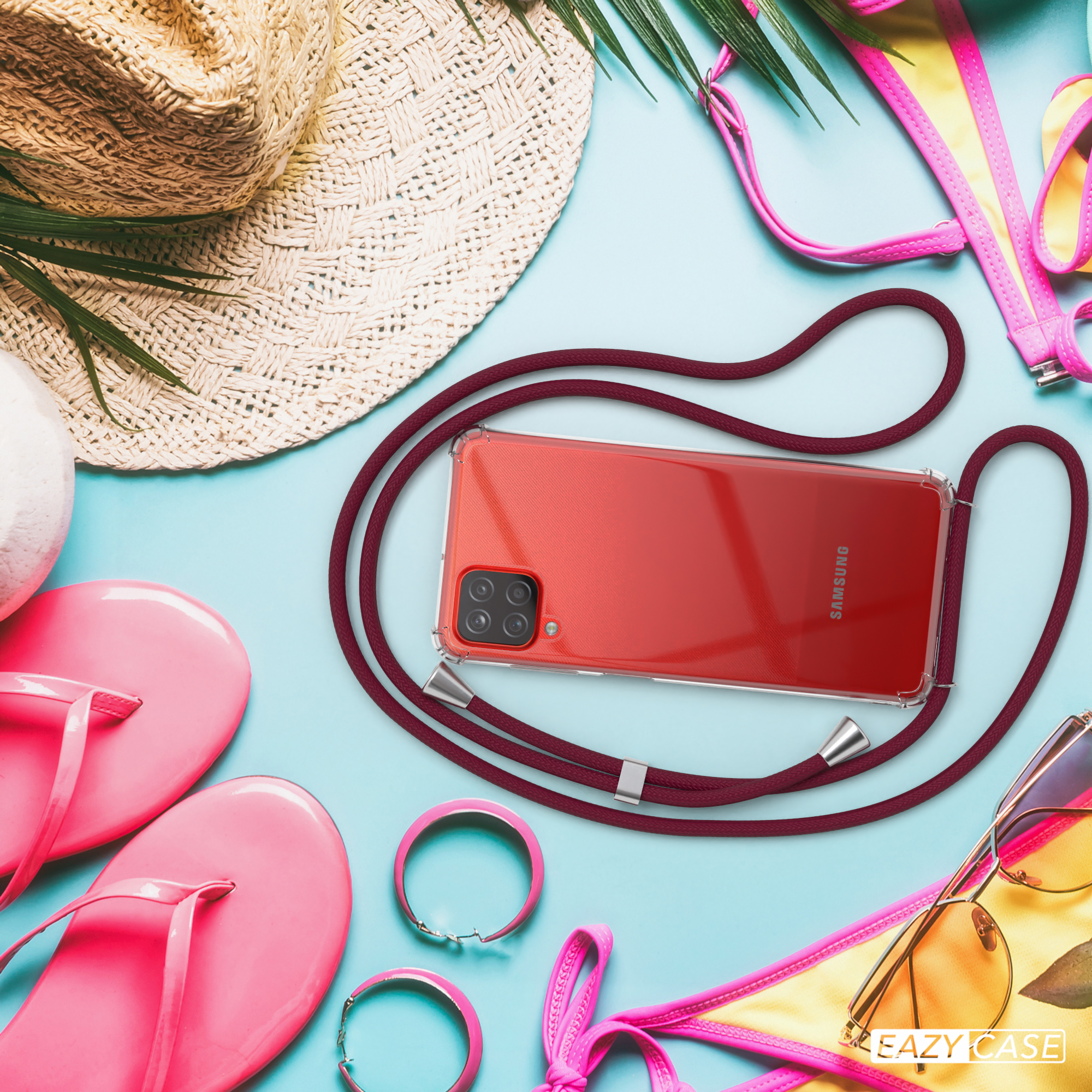 Ein rotes Telefon in einer durchsichtigen Hülle. Es ist von Strandaccessoires umgeben: Hut, Sonnenbrille und Bikini.