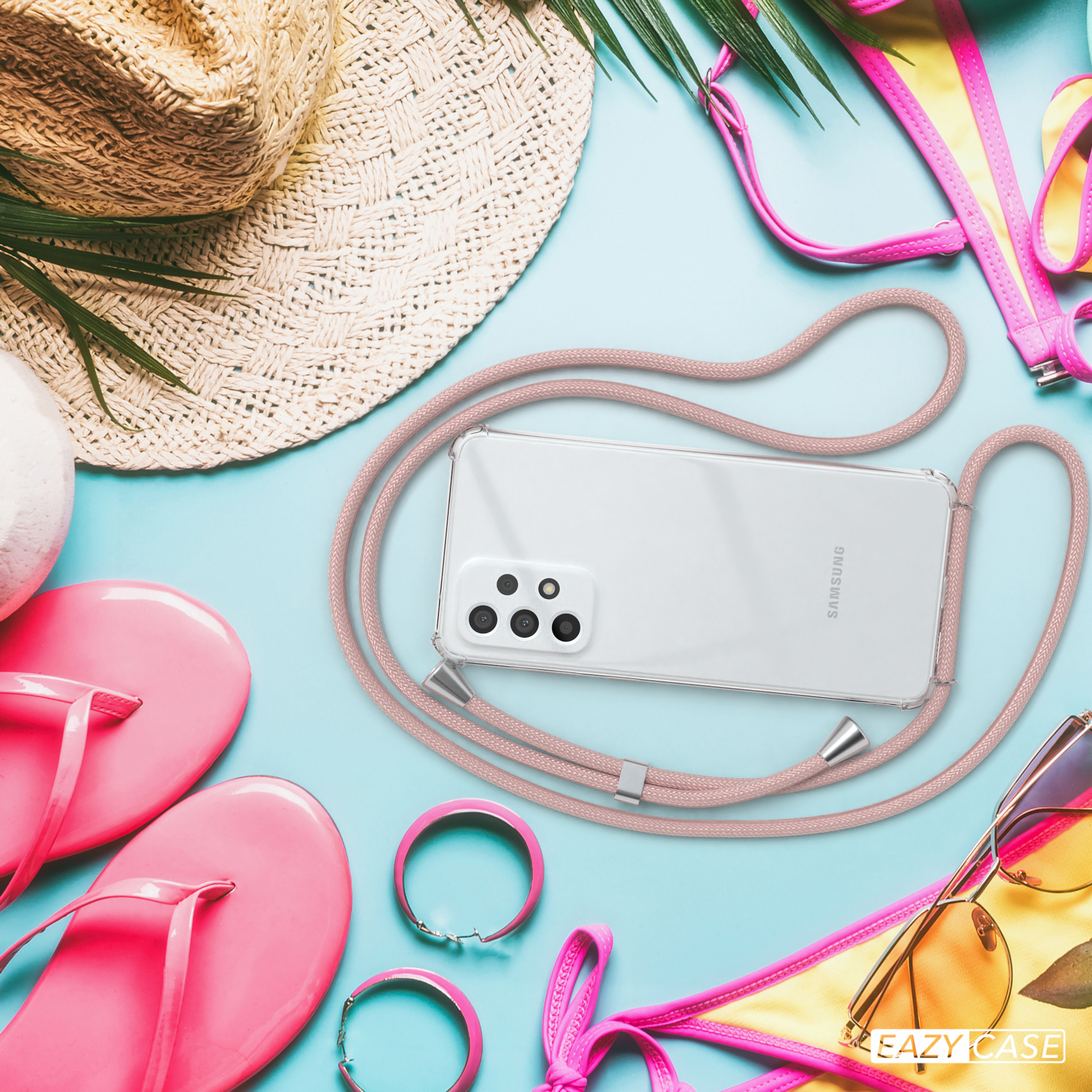 Telefon mit rosa Kordel am Strand mit Accessoires.