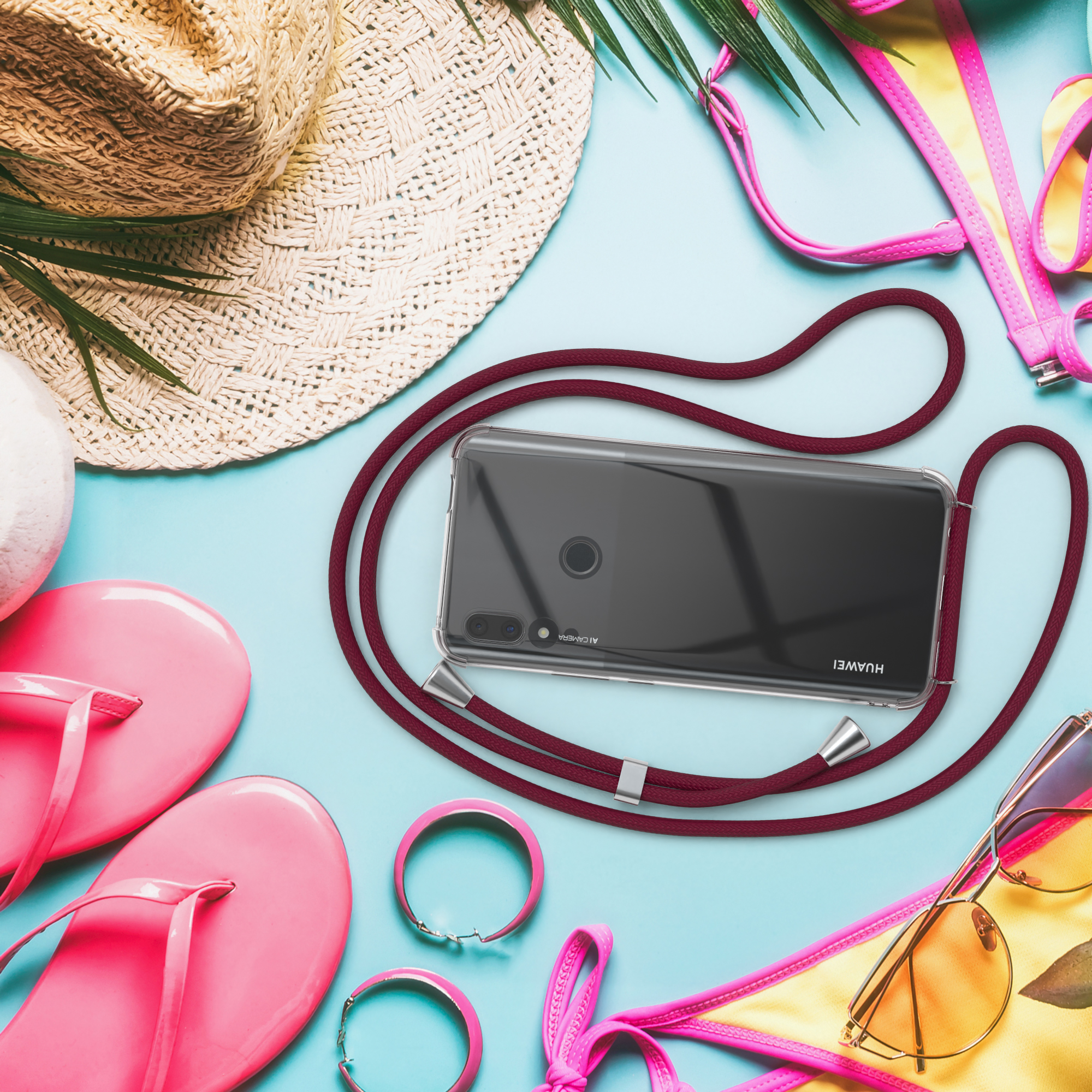 Telefon mit Hülle und roter Kordel, Hut, Flip-Flops und Sonnenbrille auf blauem Untergrund.