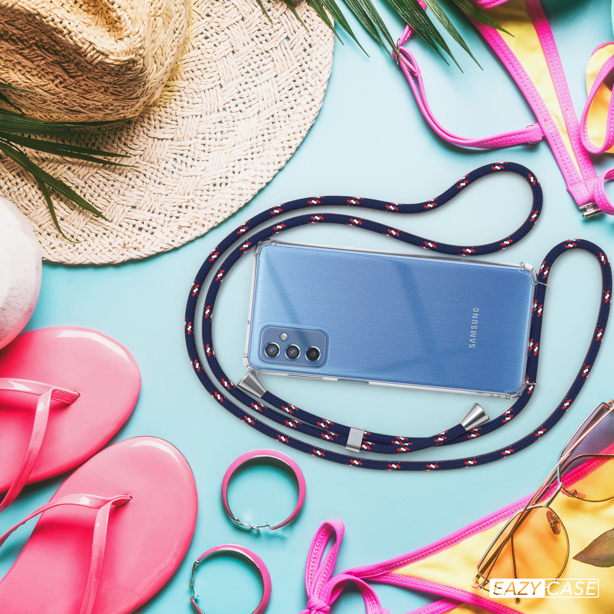 Ein Telefon mit Lanyard auf blauer Oberfläche. Sonnenbrille, Hut und Schmuck an den Seiten.