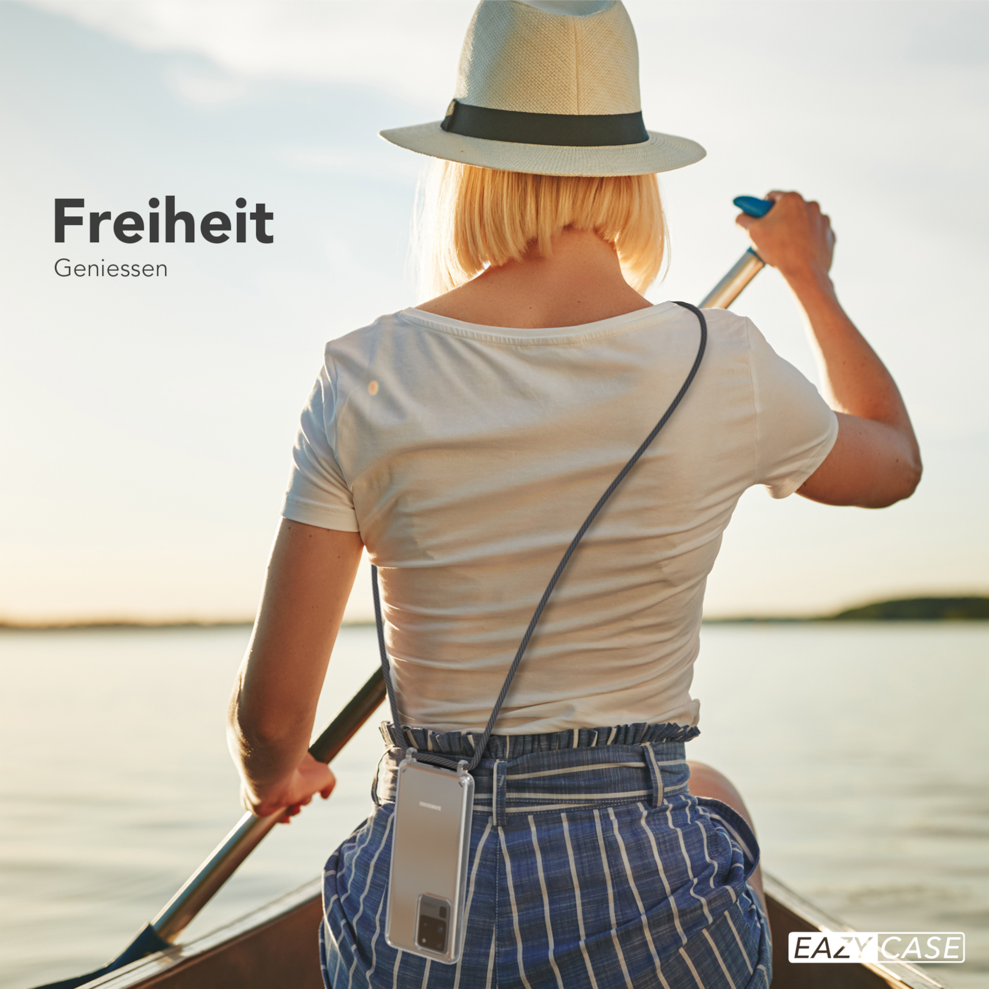 Frau beim Kanufahren, Rücken zur Kamera, Hut und Handyhülle mit Lanyard. Sonnenuntergang über dem See.