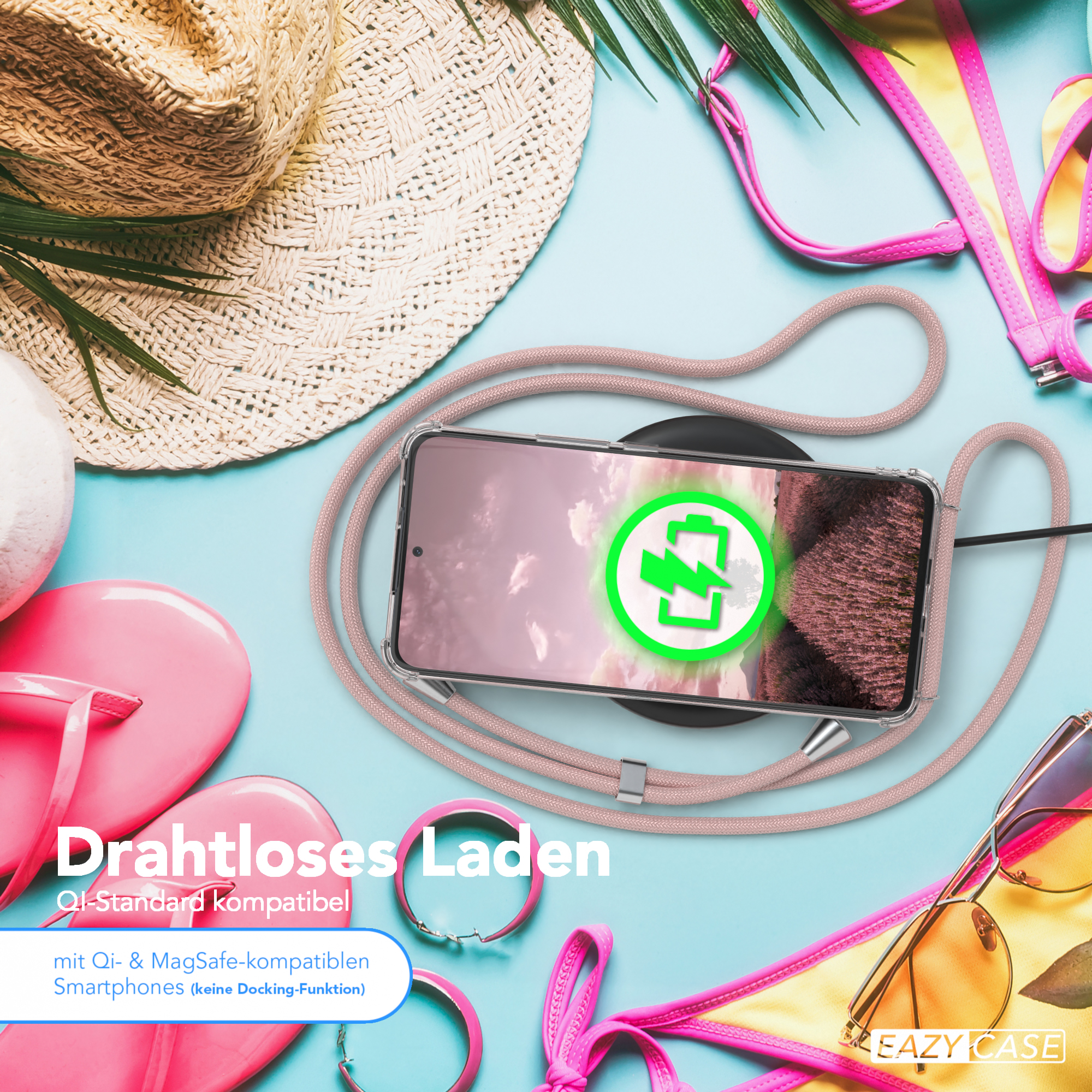 Telefon auf einem Ladegerät mit einem rosa Seil. Das Telefon ist von Strandartikeln umgeben.