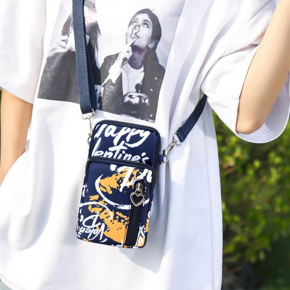Frau trägt weißes T-Shirt mit marineblauer Telefontasche. Orangefarbene Schrift auf der Tasche.
