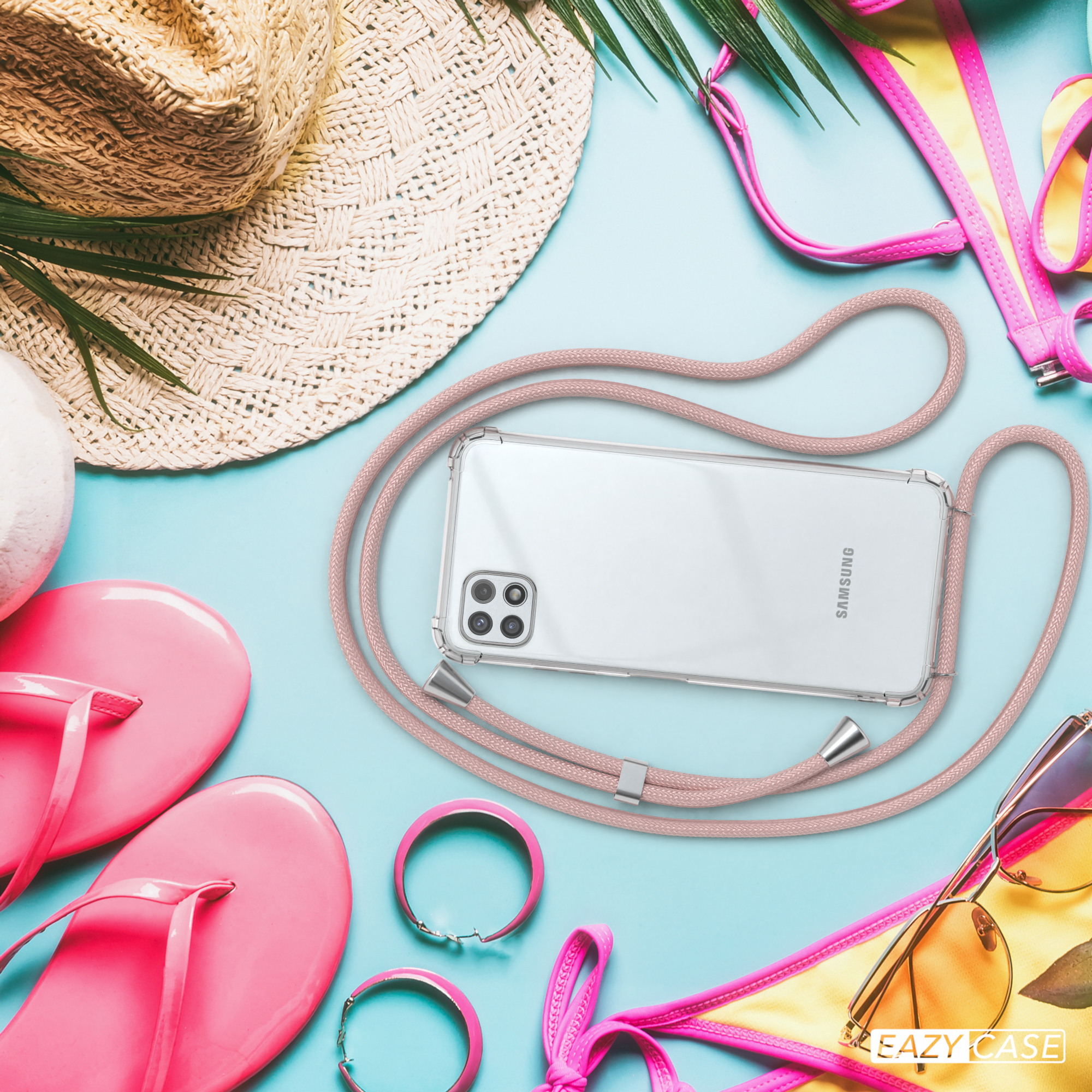 Telefon mit rosa Kordel auf blauer Oberfläche mit Strandutensilien. Text: Eazy Case. Hintergrund: Strohhut, Flip-Flops und Sonnenbrille.